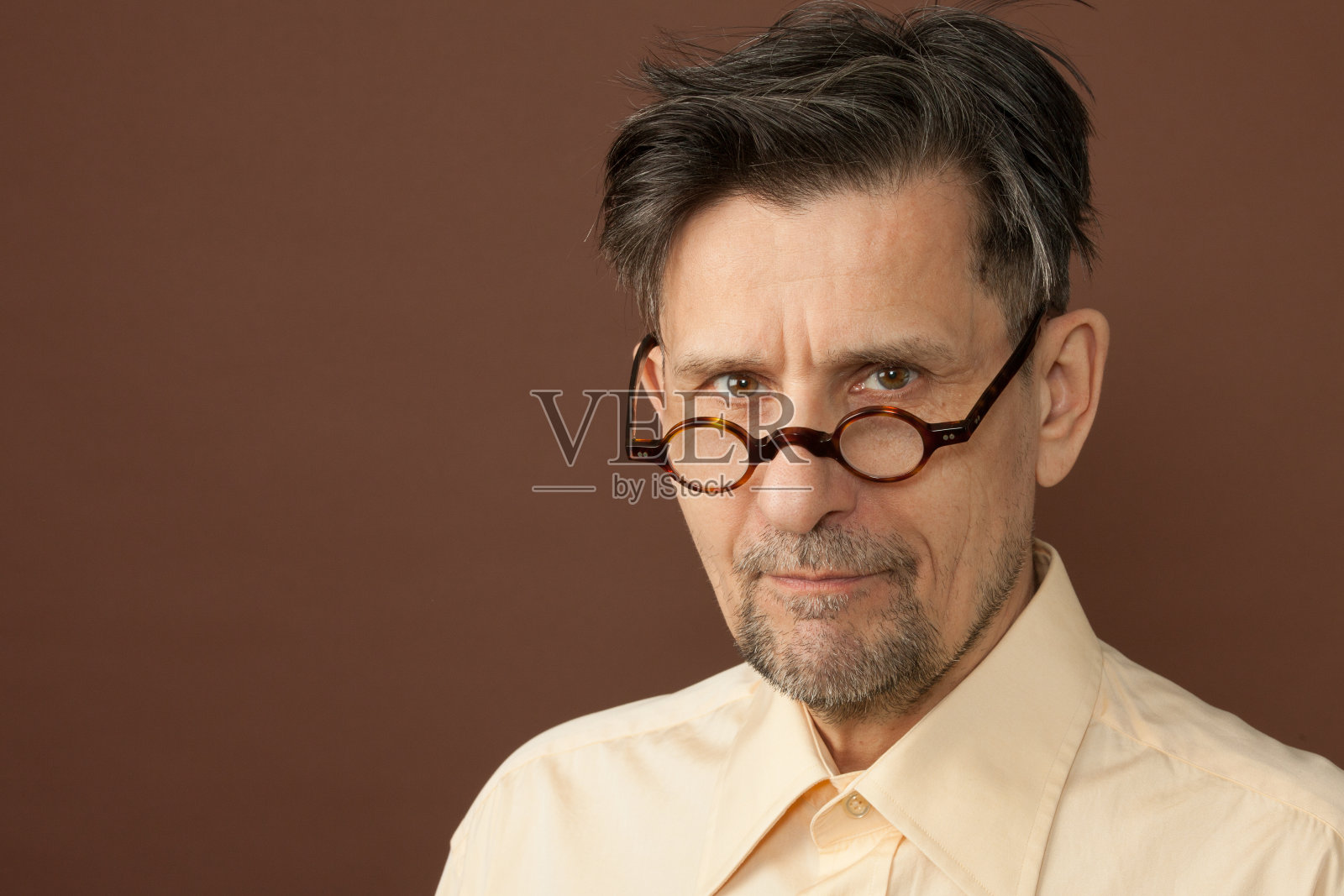 一个60岁老人在棕色背景上的工作室肖像照片摄影图片