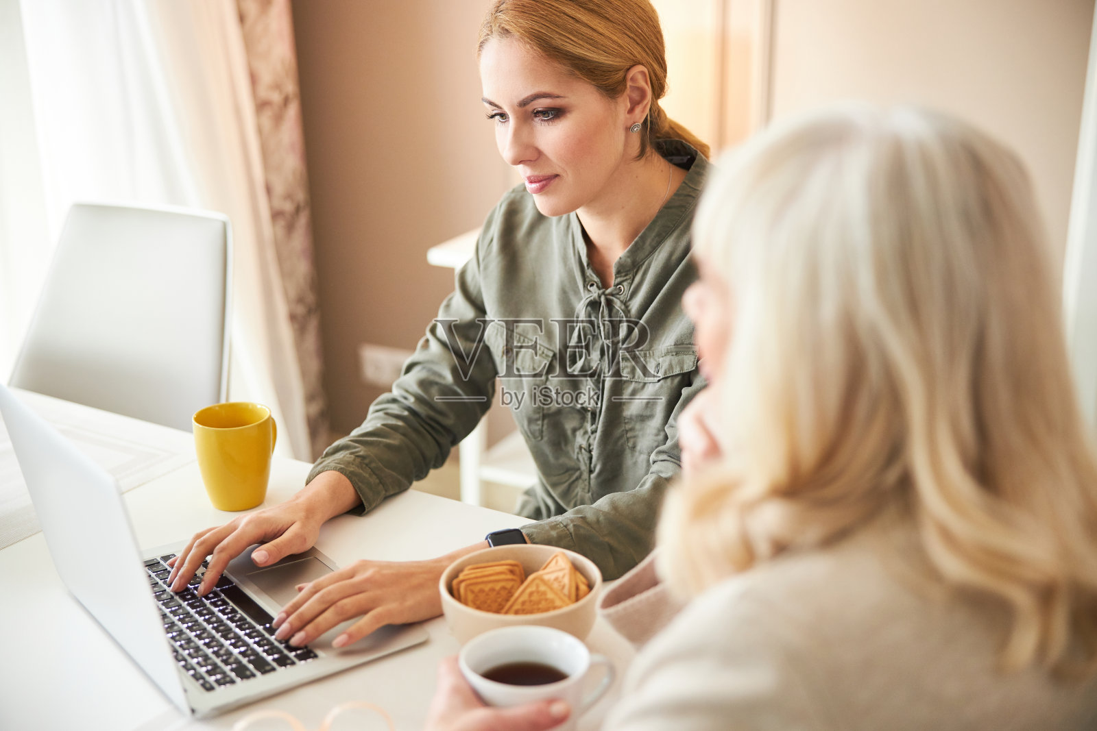 微笑的女士和年长的女性在家中使用笔记本电脑照片摄影图片
