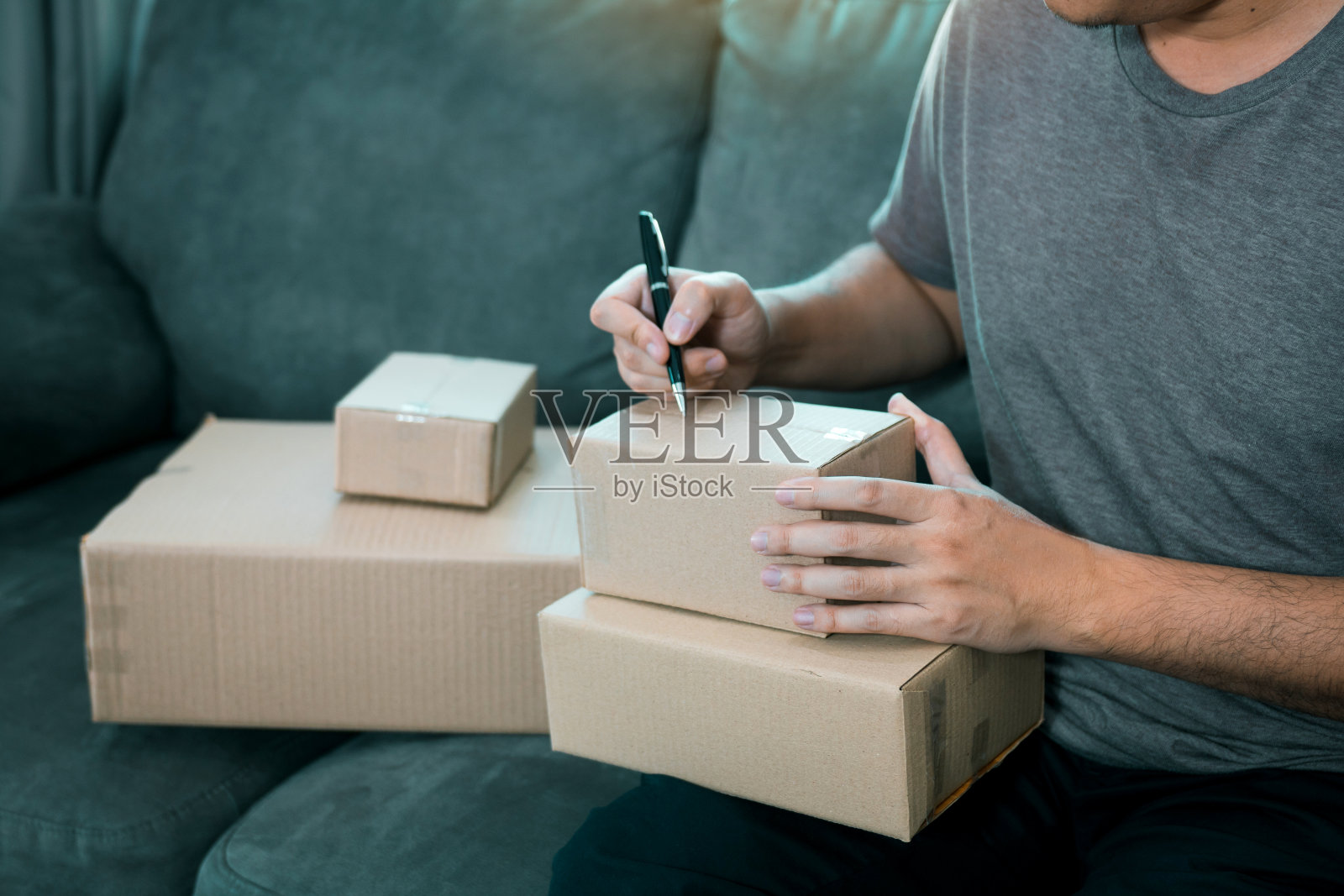 在工作场所纸箱上写地址的年轻亚洲男店主照片摄影图片