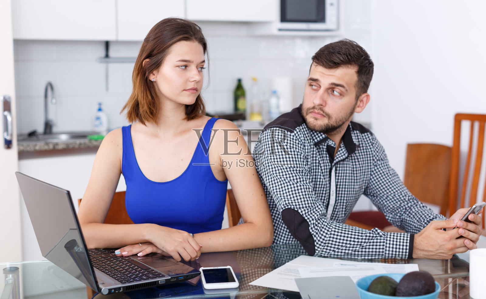 在家看笔记本电脑和男人玩手机的年轻女人照片摄影图片