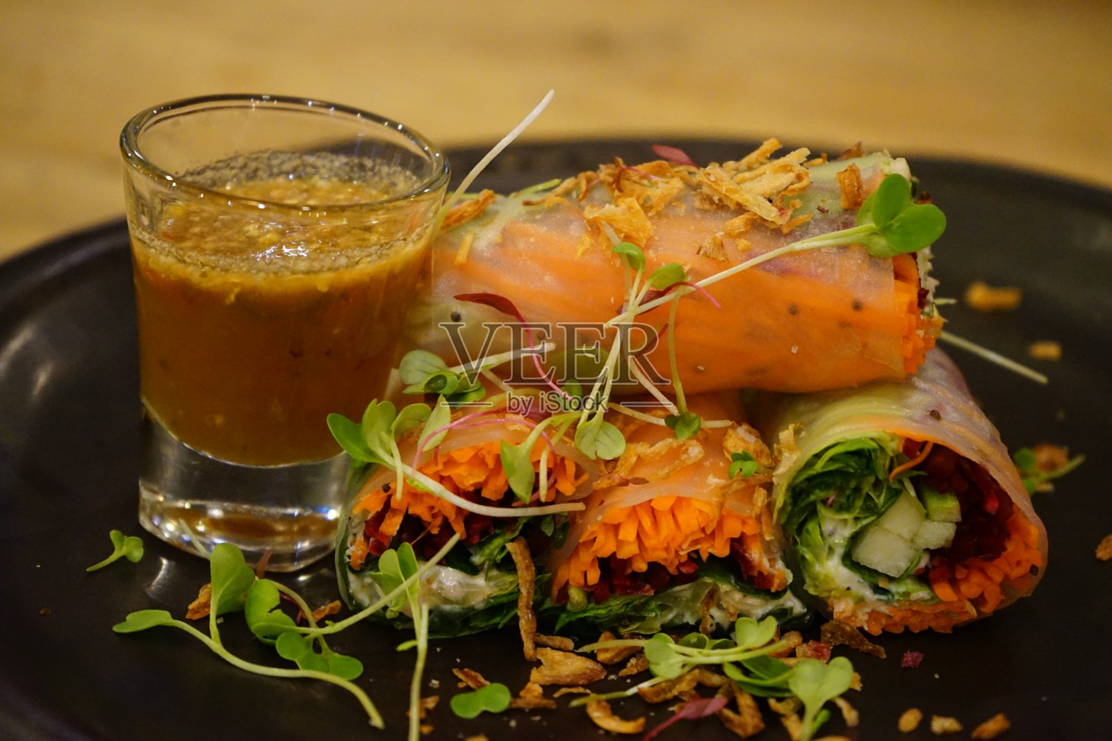 健康的沙拉卷装在一个黑色的盘子里，放在一个模糊的木桌上照片摄影图片