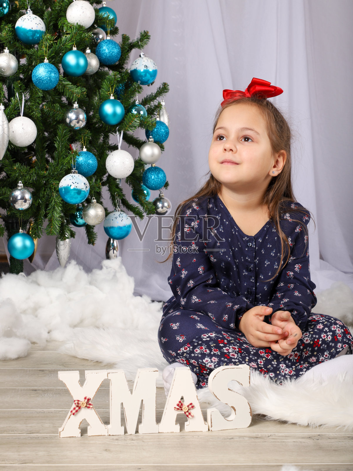 圣诞树前的穿紫色连衣裙的可爱小女孩照片摄影图片