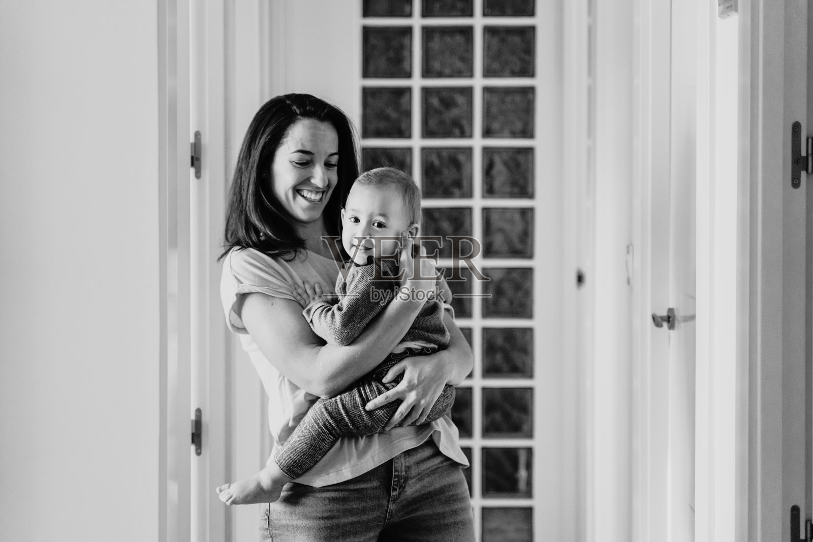 年轻的母亲在家和一岁大的可爱女婴玩耍，享受家庭时光照片摄影图片