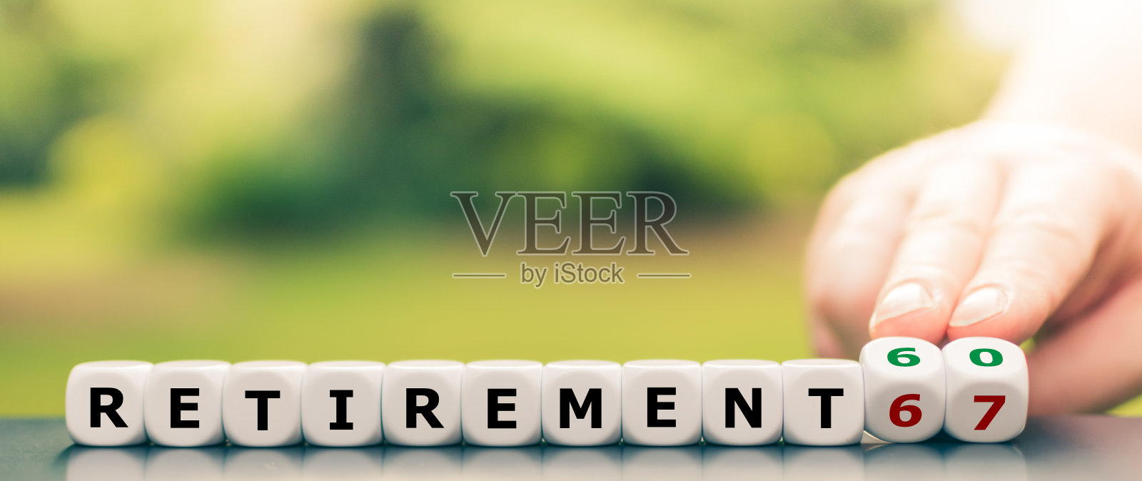 手转动骰子，将“退休67”变为“退休60”照片摄影图片