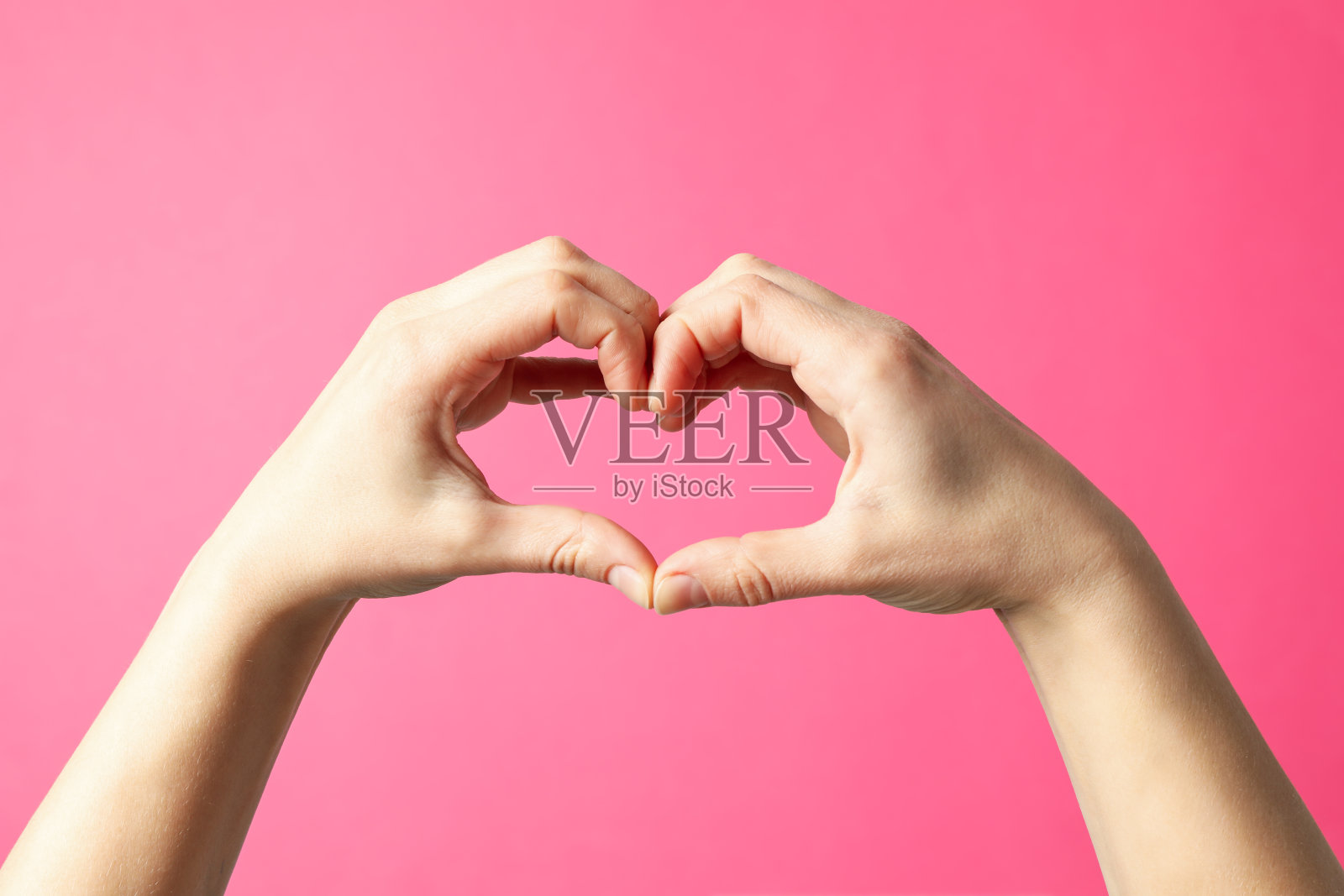 女人在粉色背景上手比爱心照片摄影图片