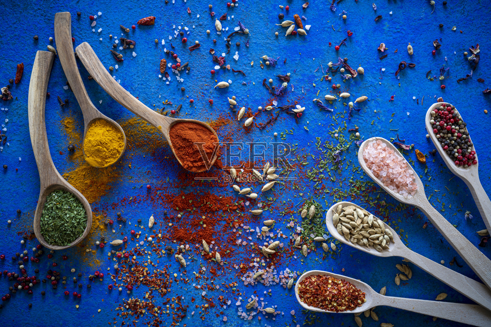 在蓝色背景的木勺上放香料、香草和调味品照片摄影图片