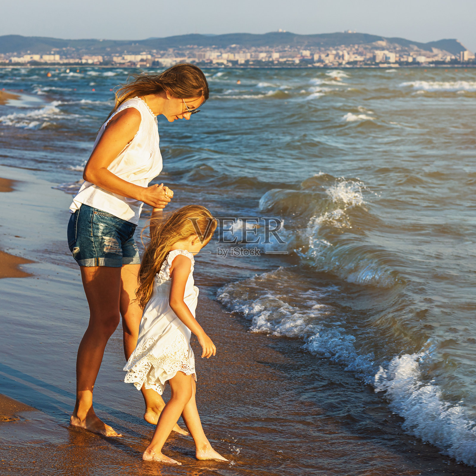 母女checking 海水是温暖还是凉爽照片摄影图片