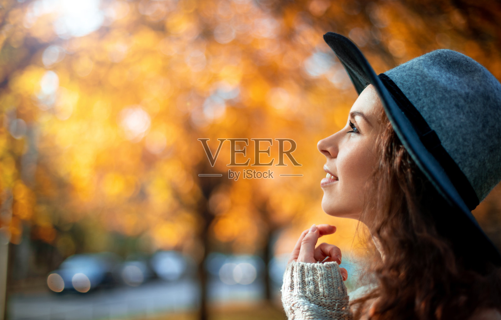 漂亮的女孩戴着帽子站在五彩缤纷的秋叶背景上照片摄影图片