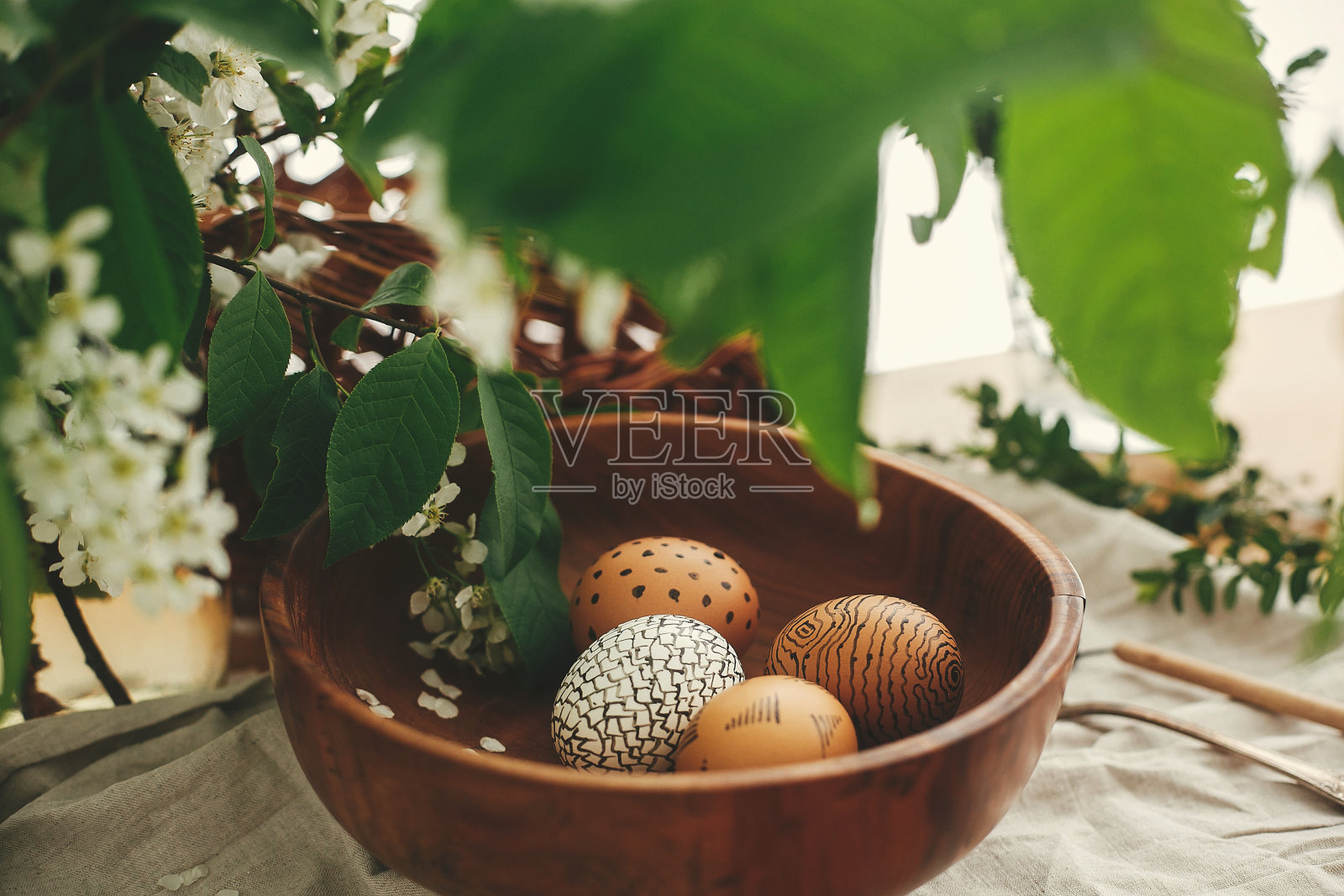 复活节假期零浪费。木碗里用蜡画的复活节彩蛋，柳条篮子为背景，木桌上放着白色的春花。复活节快乐。农村仍然生活。生态照片摄影图片