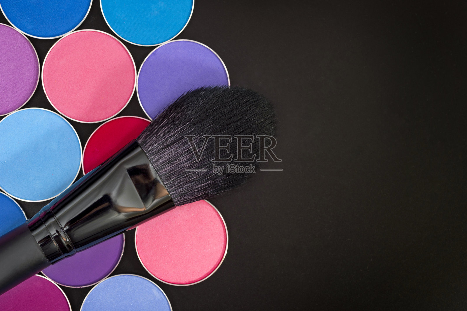 在黑色背景上使用化妆刷和彩色眼影。空间的文本。照片摄影图片