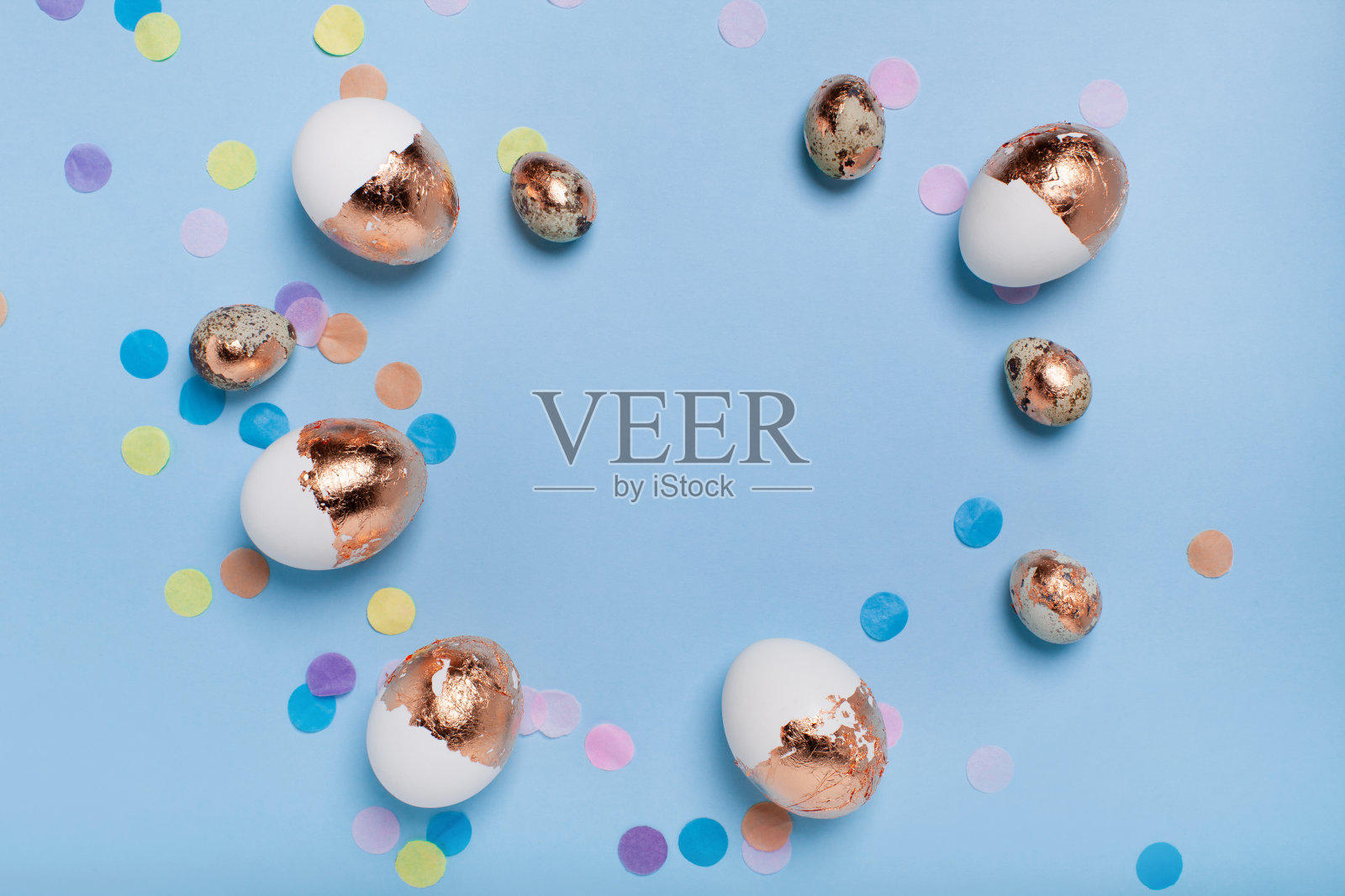 可爱的浅蓝色背景与镀金的鸡蛋和五彩纸屑照片摄影图片