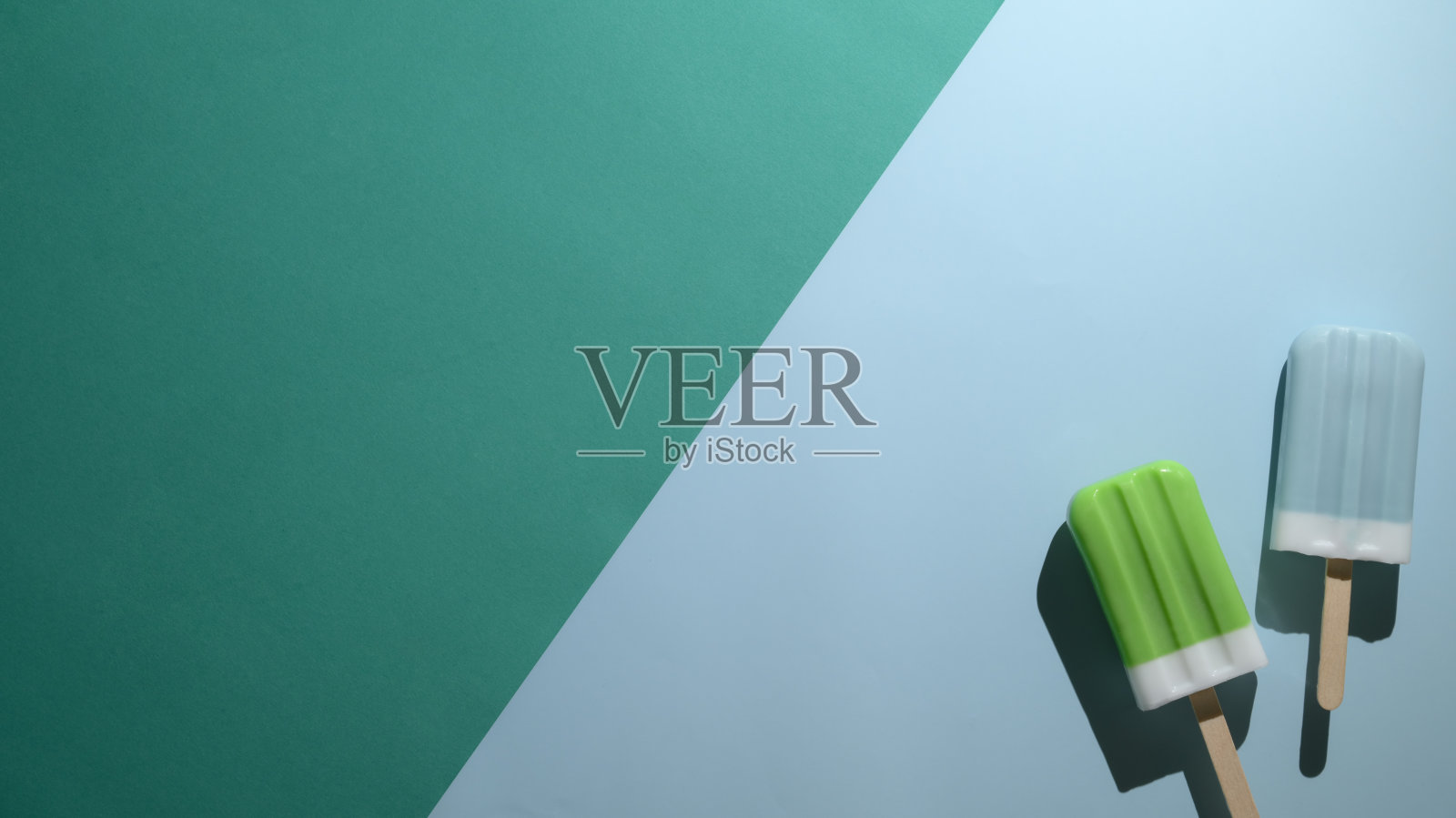 俯视图的酸橙和蓝色覆盆子味冰棒在平坦的lay绿色和蓝色背景照片摄影图片