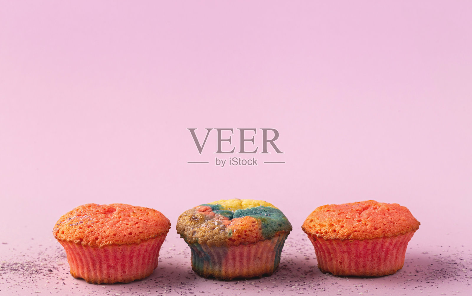 三个彩色的松饼在一个柔和的粉红色背景与复制空间照片摄影图片