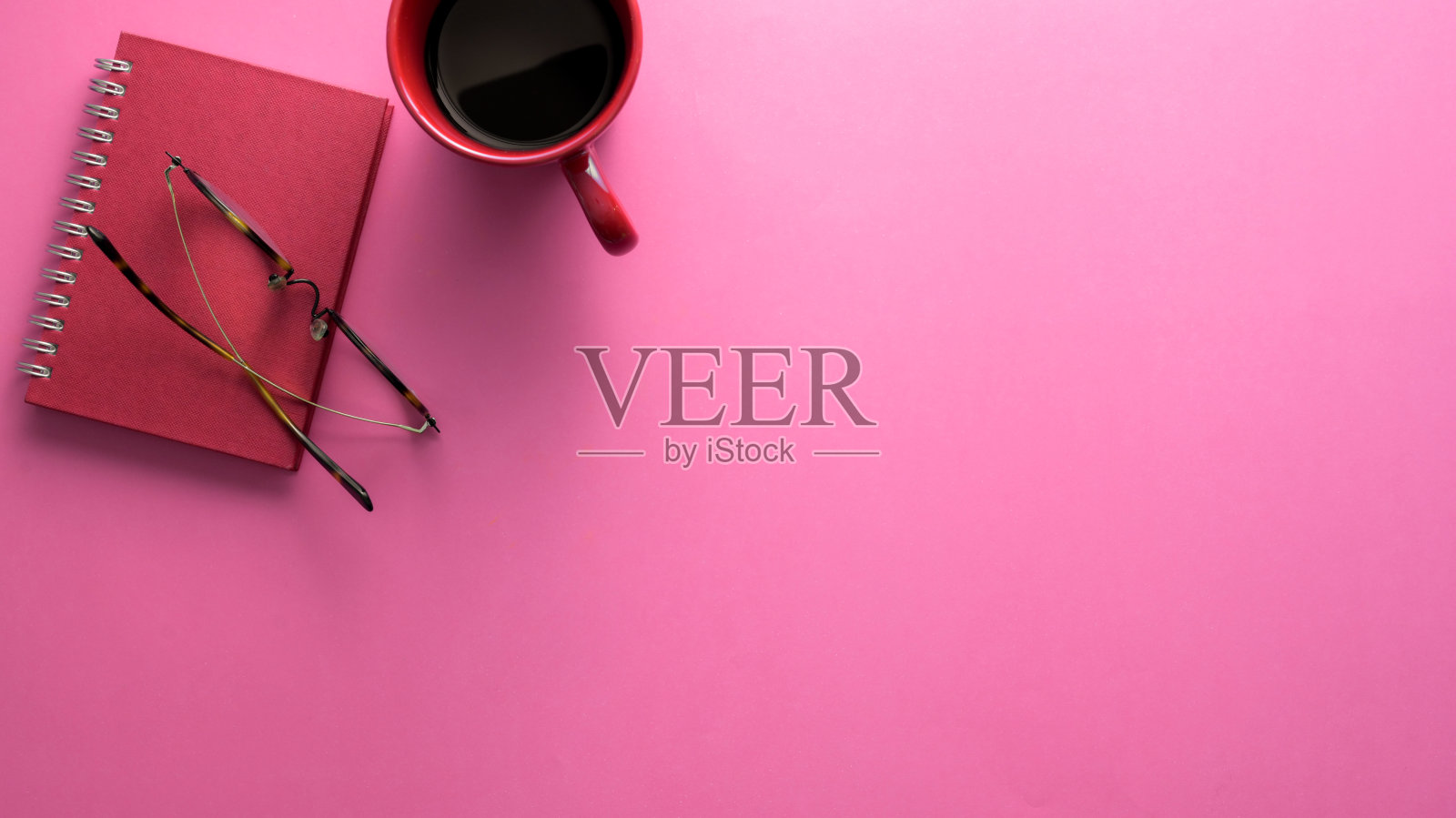 顶视图的工作空间与笔记本，眼镜，咖啡杯和复制空间在粉红色的桌子上照片摄影图片