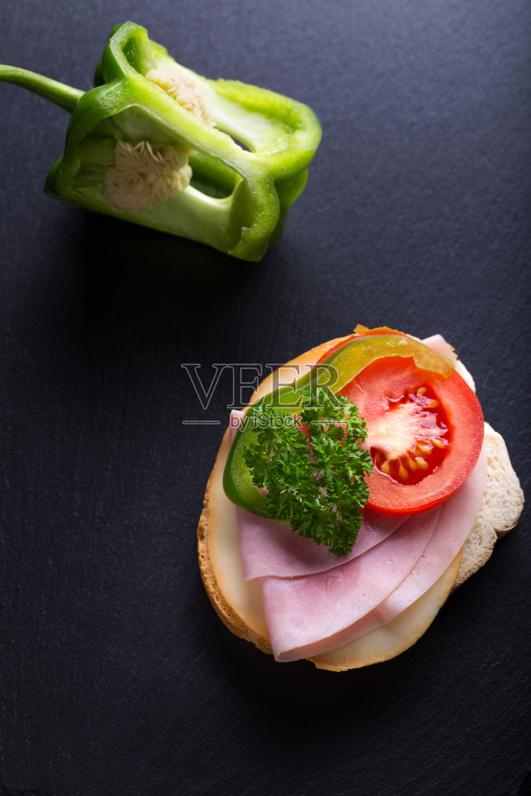 面包配火腿、番茄和青椒，黑底照片摄影图片