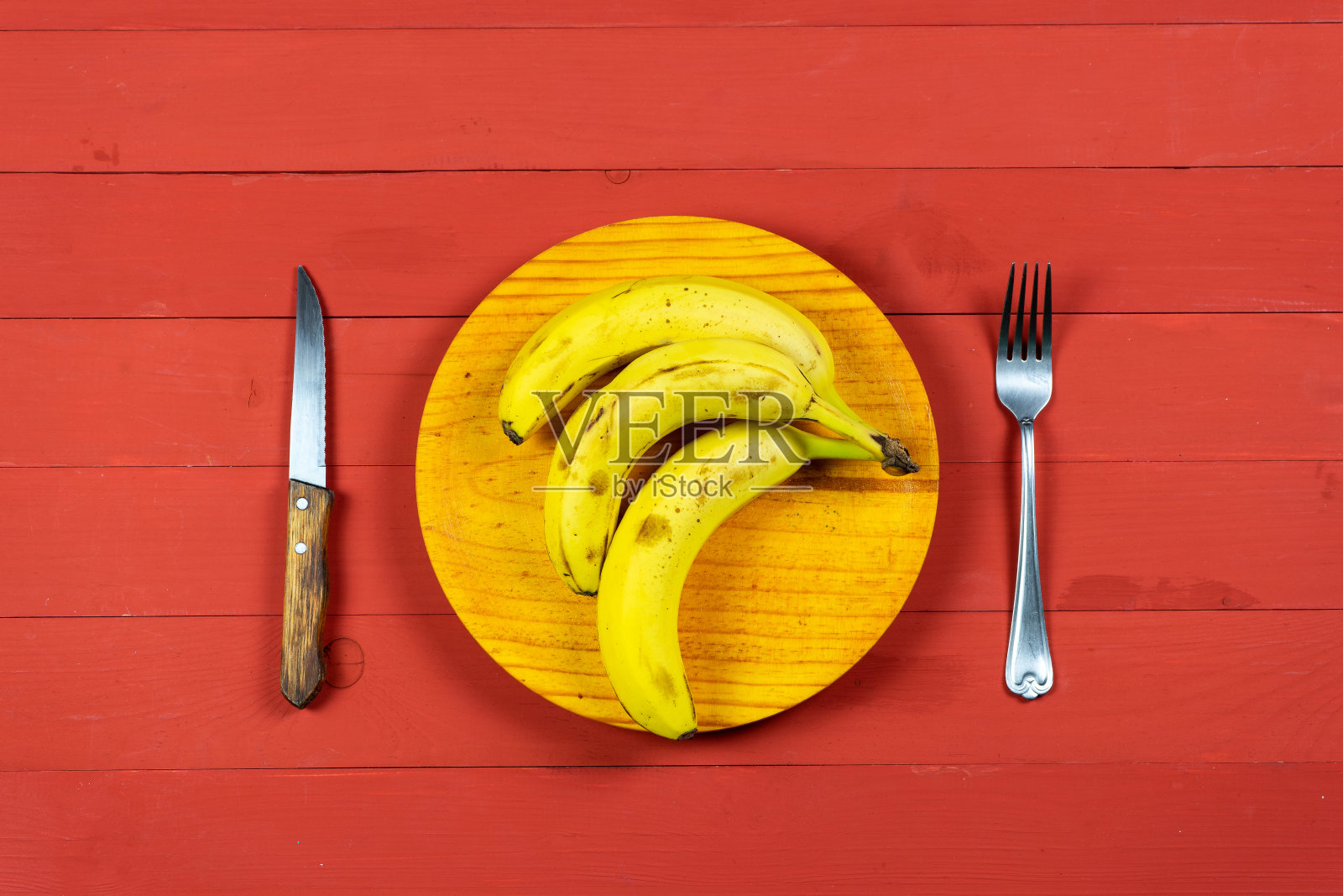 红木桌上放着成熟的香蕉和刀叉照片摄影图片