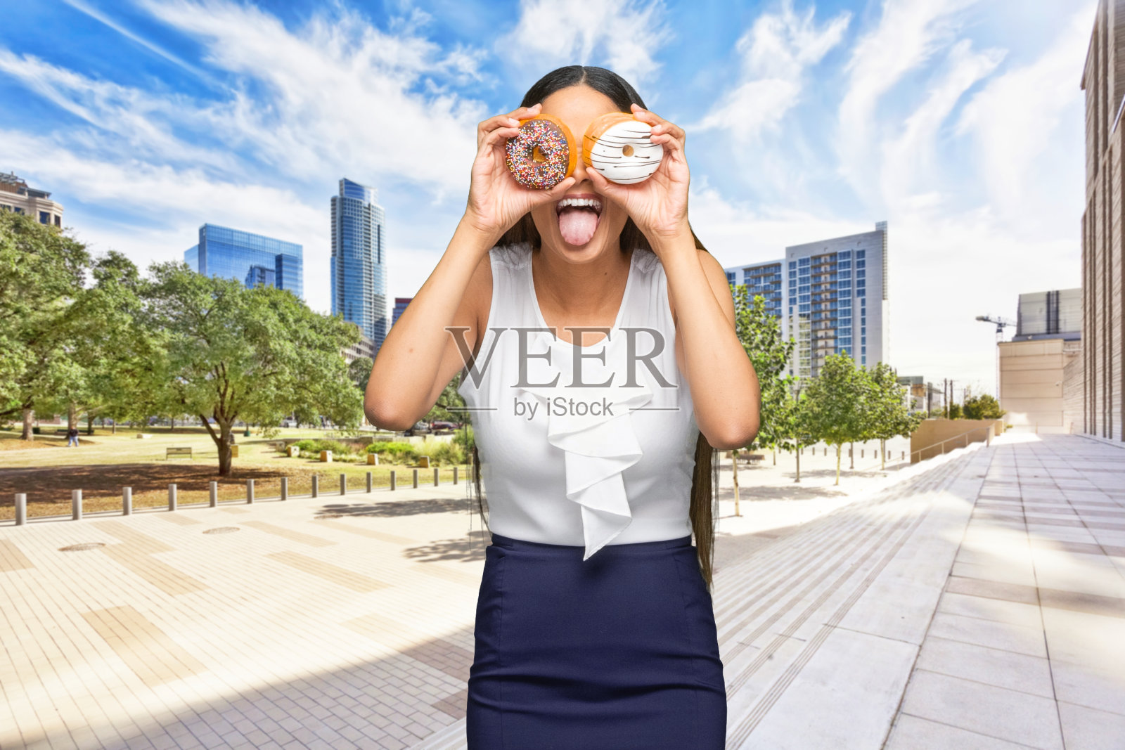 非裔美国人青年女商人，户外站立，穿着商务休闲装，手持甜甜圈照片摄影图片