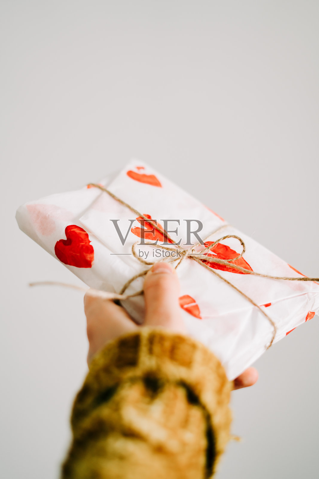 这是一件女子亲手制作的礼物，包裹在自制的包装纸中，上面用黄麻线系着红心，是情人节的礼物照片摄影图片