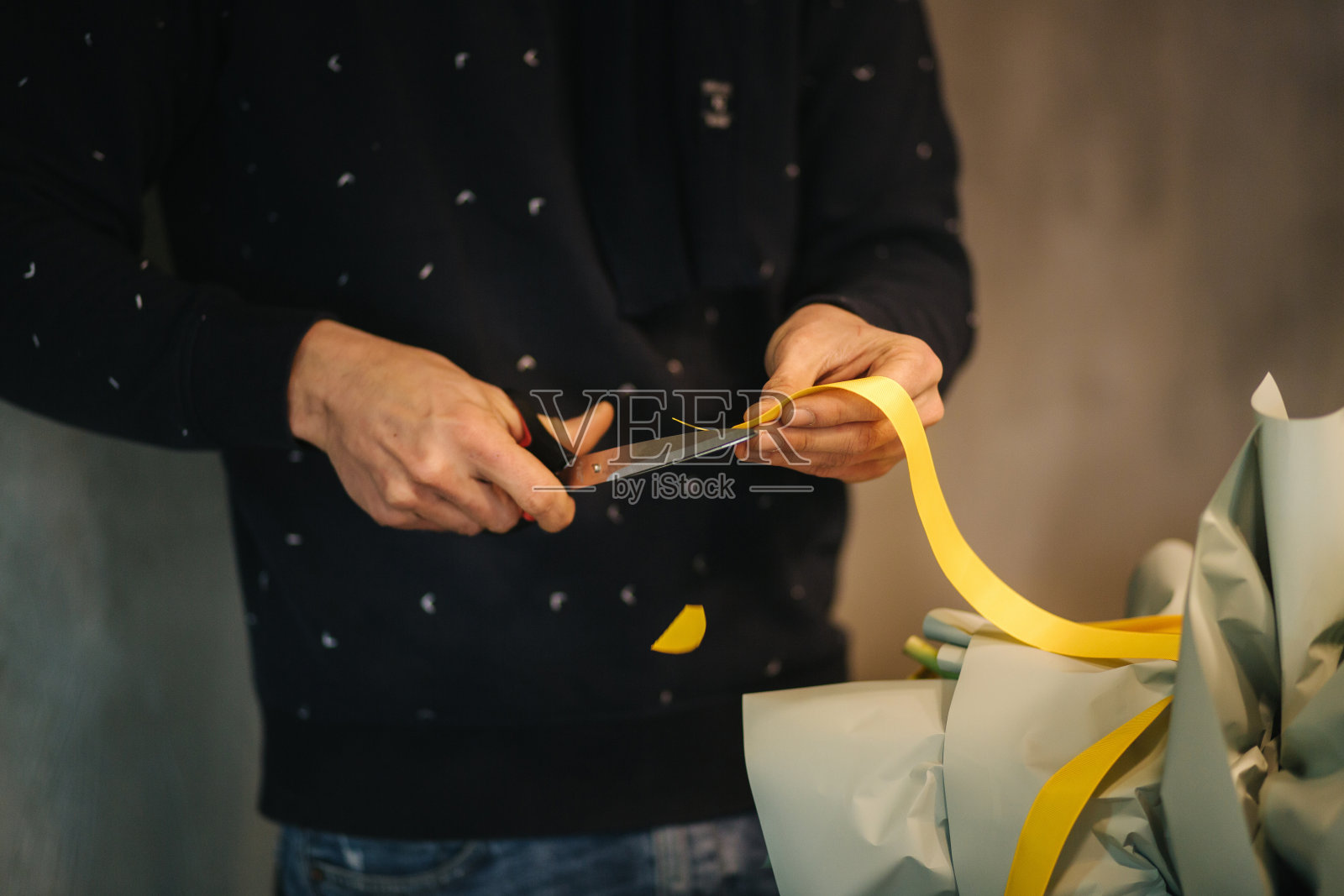 男人制作春季花束：用黄色丝带扎花照片摄影图片