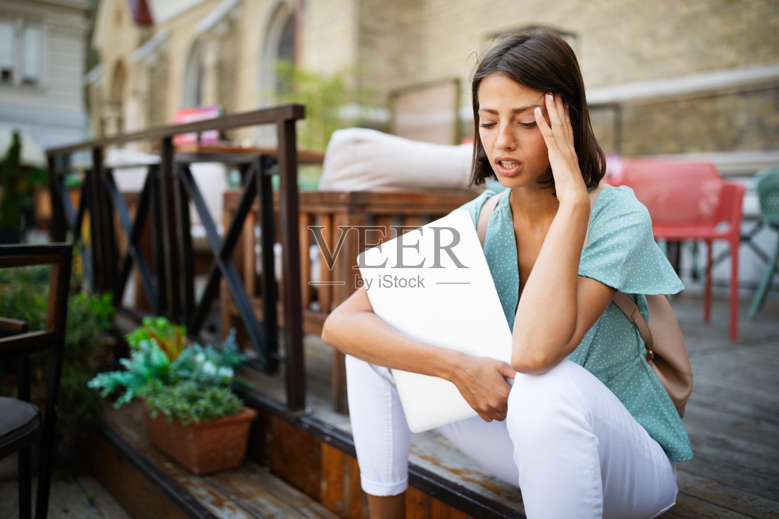 沮丧悲伤的年轻女人感到疲倦，担心坐在笔记本电脑旁的问题照片摄影图片