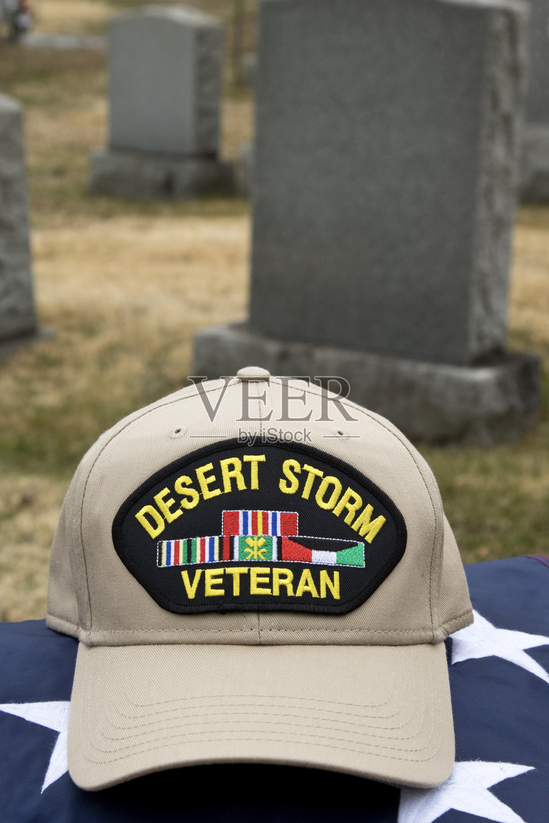 沙漠风暴老兵的帽子躺在墓地的美国国旗上。照片摄影图片