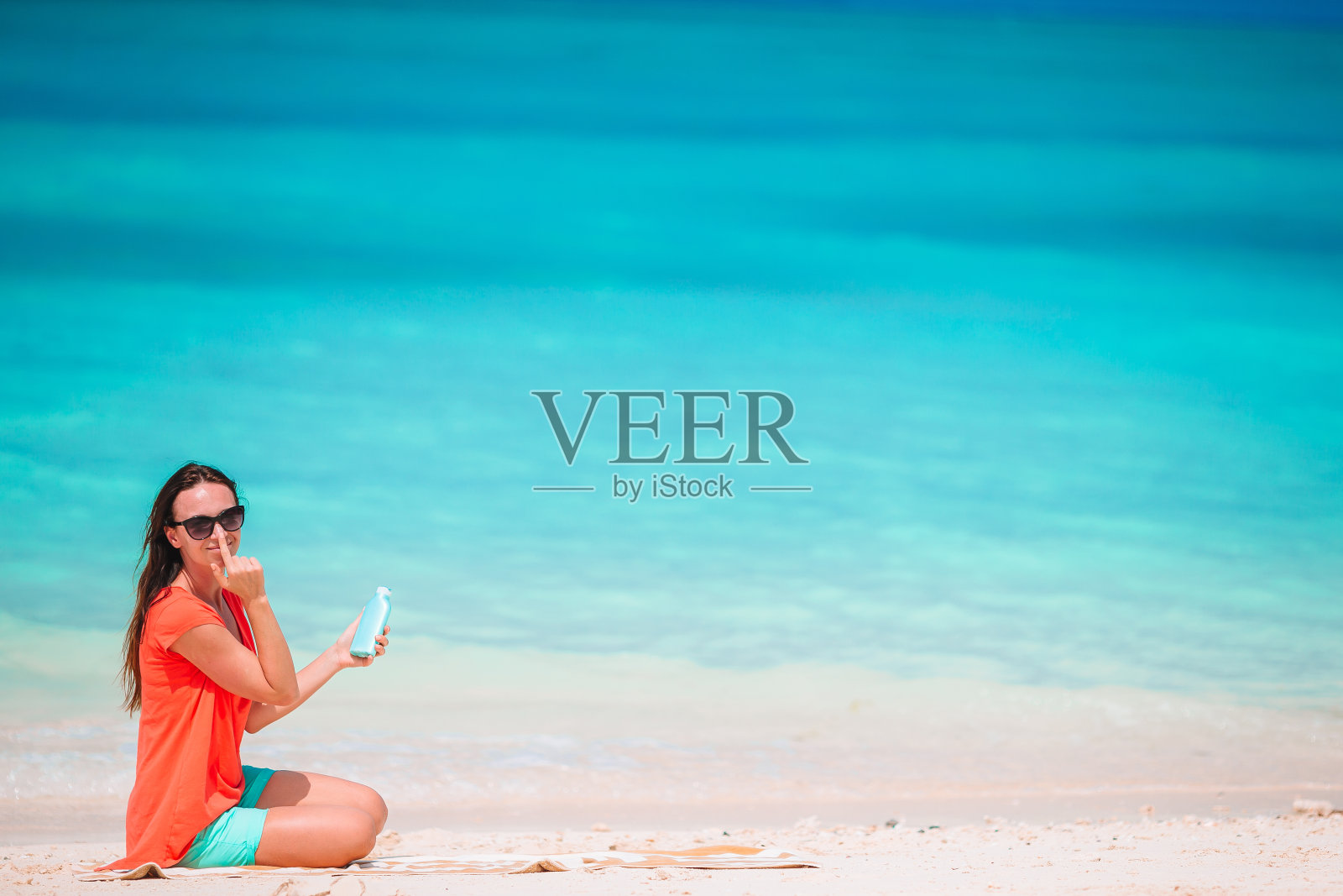 年轻女子在热带海滩上拿着防晒霜照片摄影图片