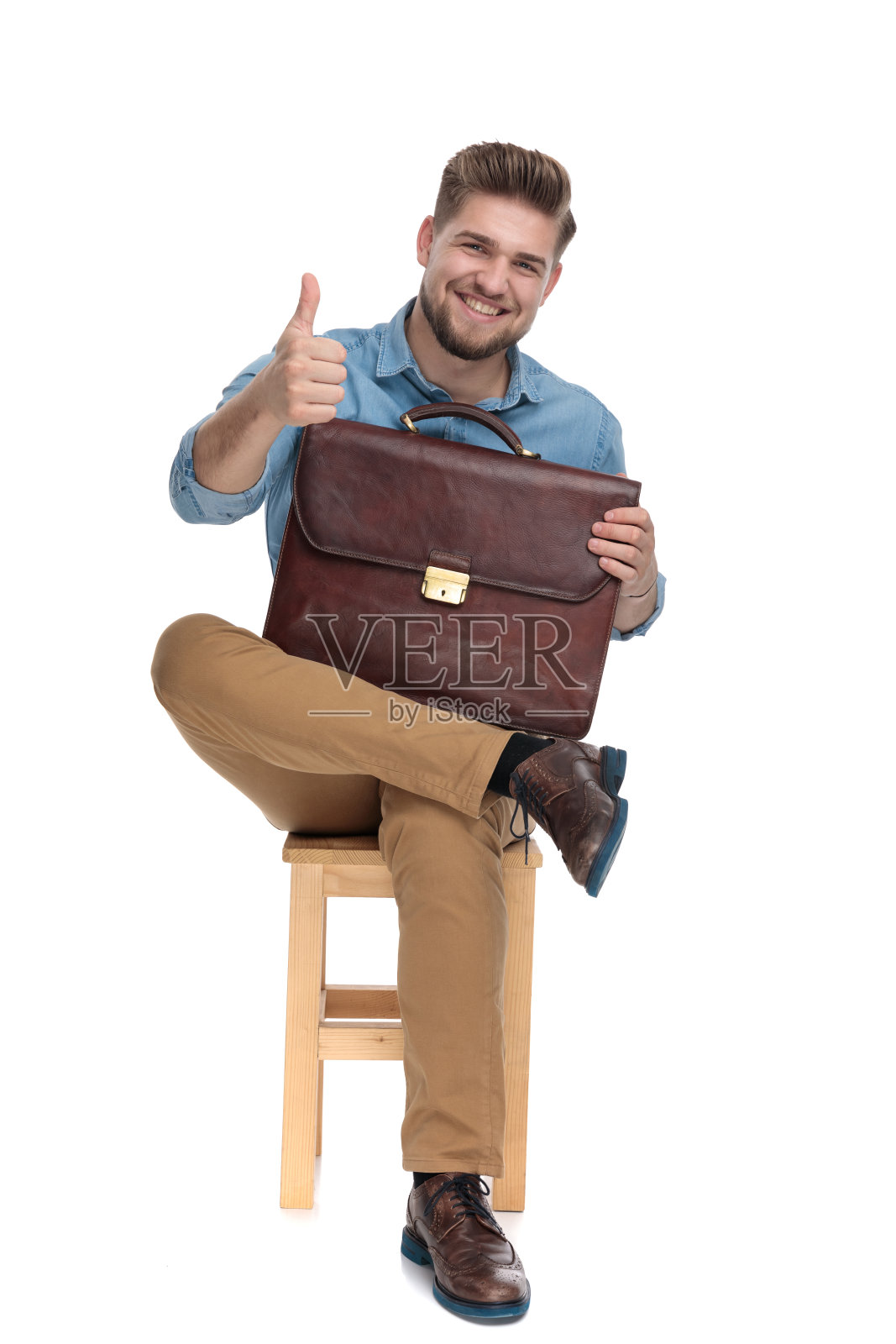 微笑的年轻男子竖起大拇指，拿着手提箱照片摄影图片