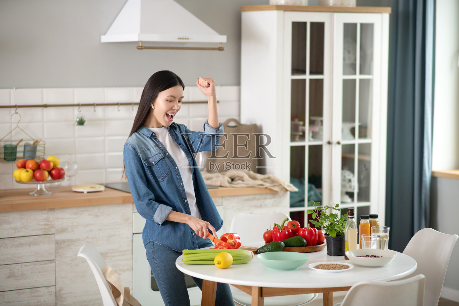 快乐的年轻女子正在切红甜椒。照片摄影图片