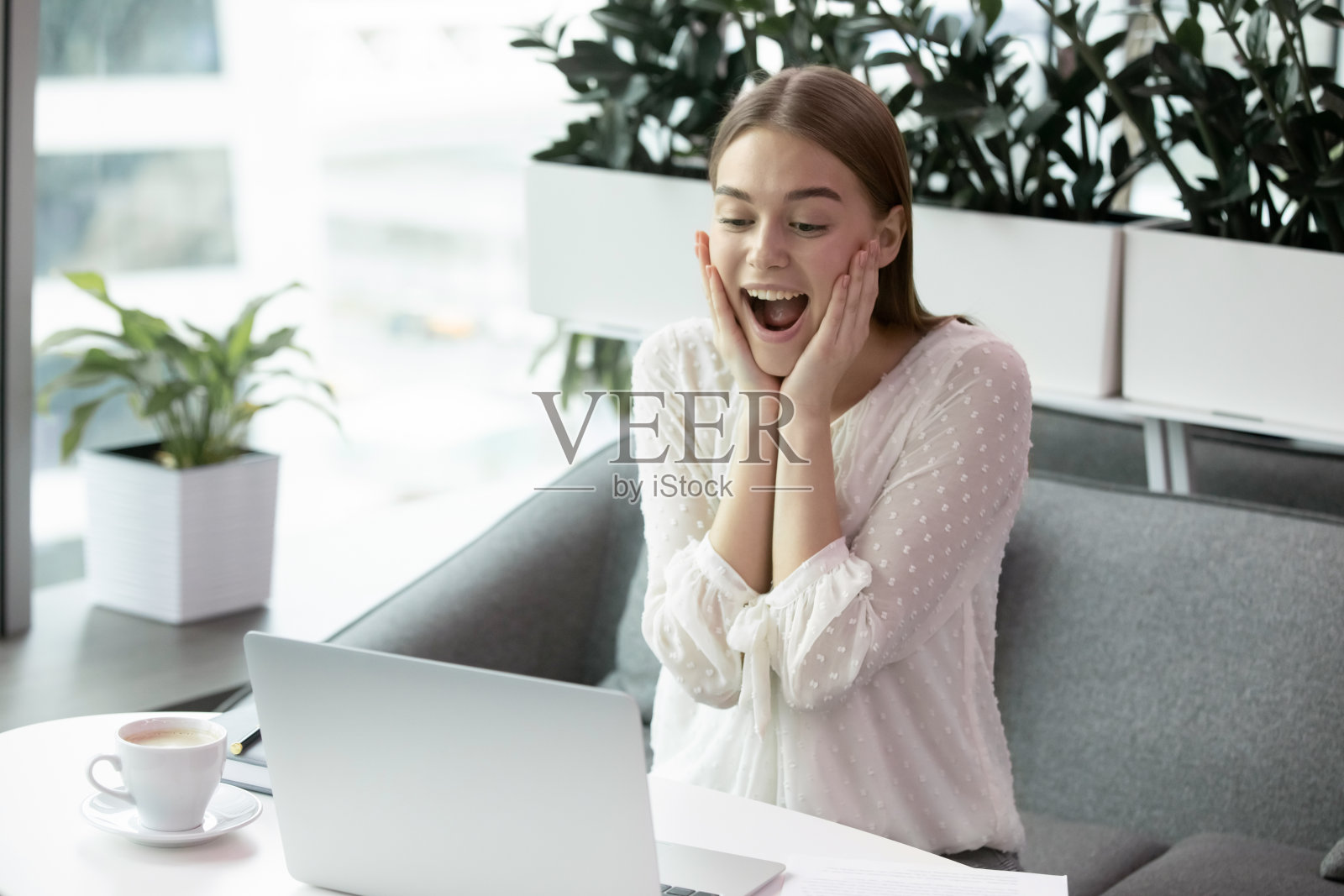 兴奋的年轻女子感觉惊讶，看着电脑屏幕。照片摄影图片