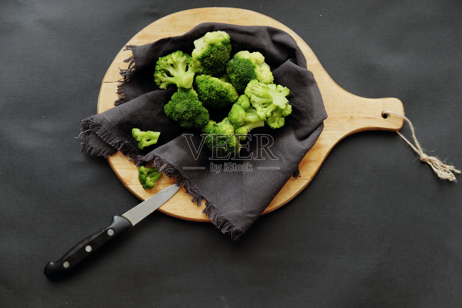 健康早餐:在深色背景上的木板上画着新鲜生的西兰花。照片摄影图片