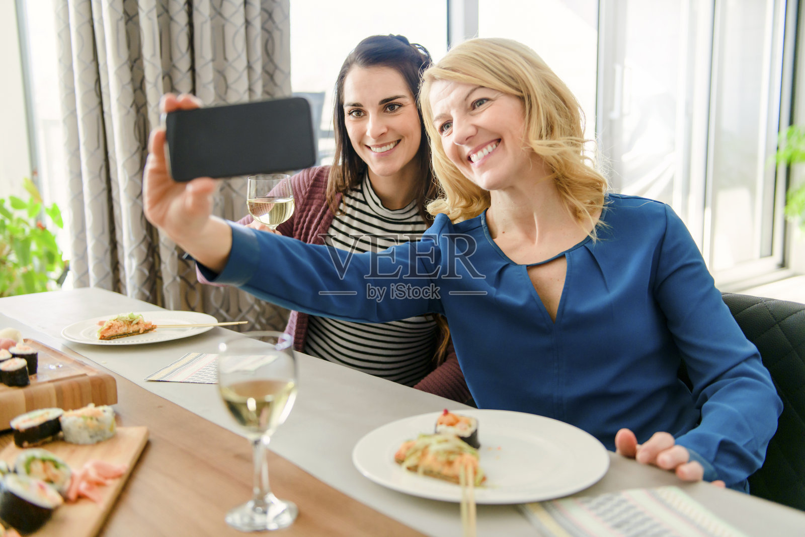 两个有魅力的中年人在家吃寿司并拍照照片摄影图片