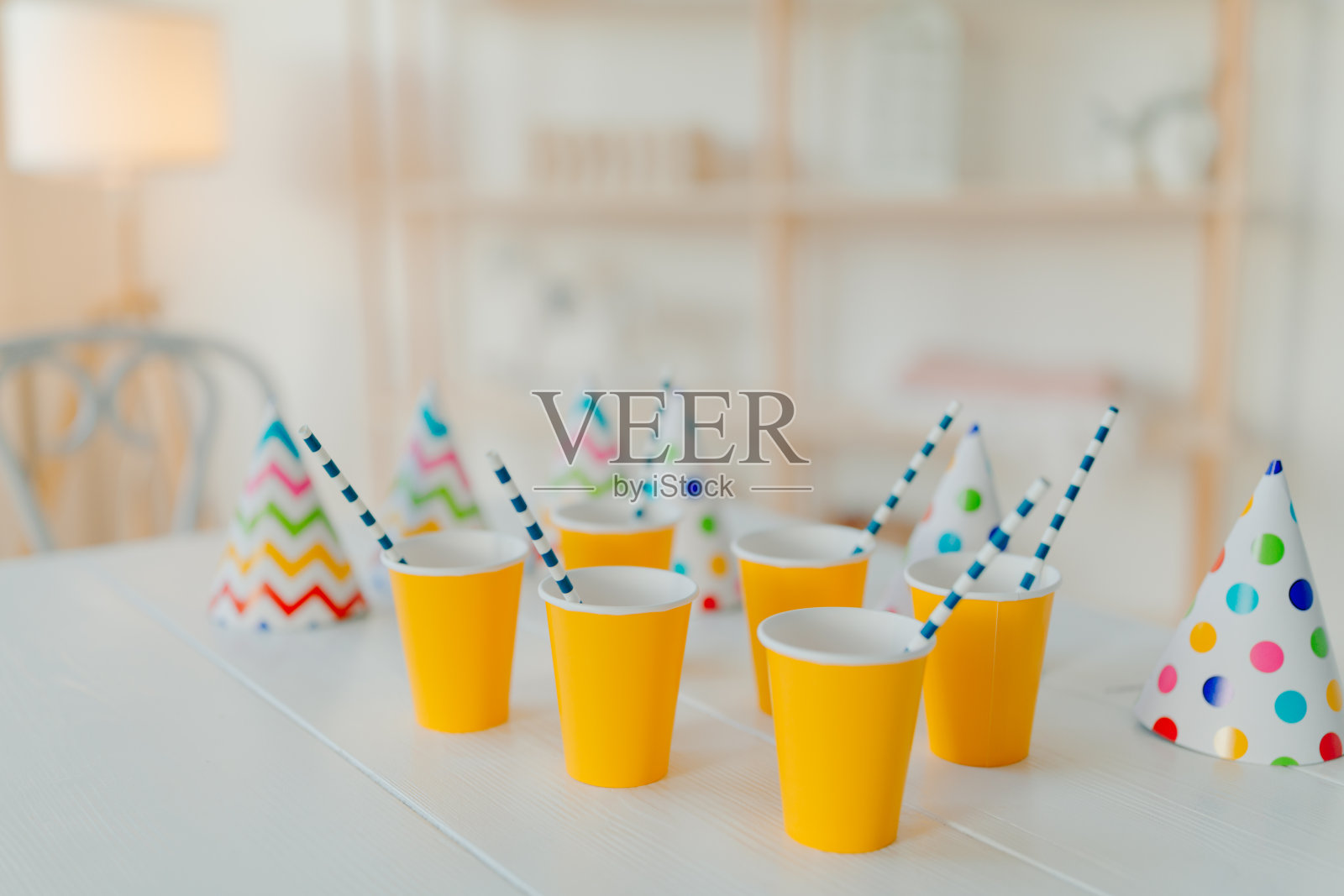 白色的桌子上放着节日帽子和纸杯，纸杯上有饮料和吸管。节日活动。生日聚会庆祝概念。模糊的背景。没有人在照片照片摄影图片