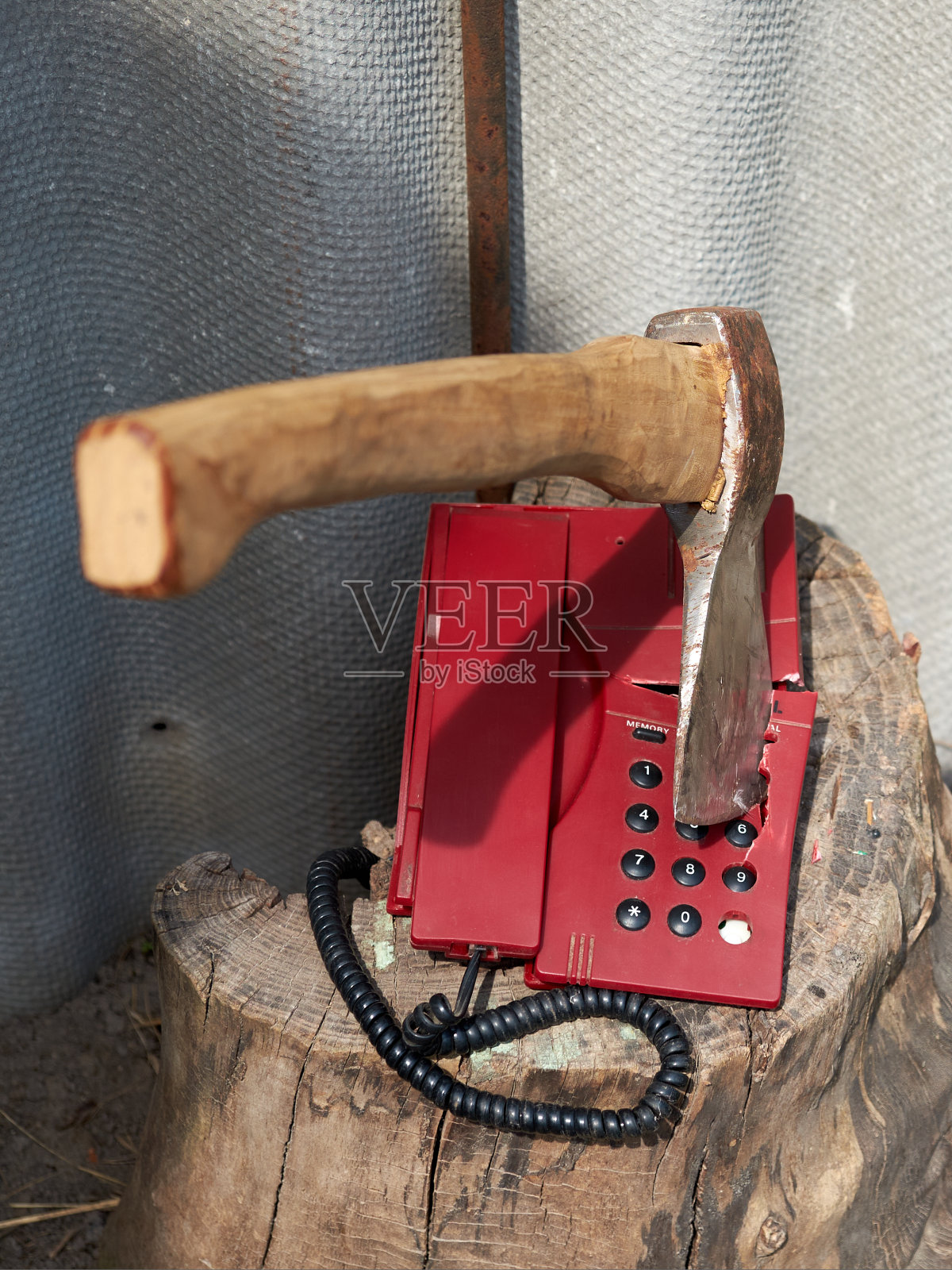 老式的按键式电话里伸出一把大斧头。照片摄影图片