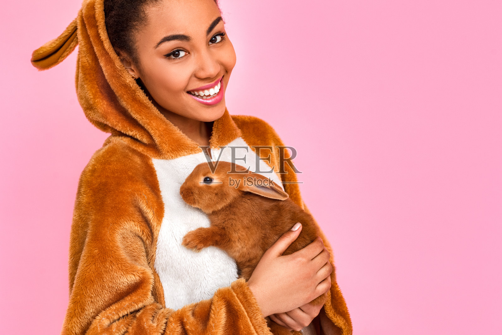 自由泳。年轻女子在基古umi孤立站在粉红色的拥抱兔子微笑牙齿近距离照片摄影图片