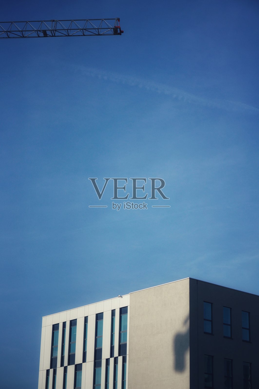 蓝天上的办公大楼和起重机的臂膀照片摄影图片