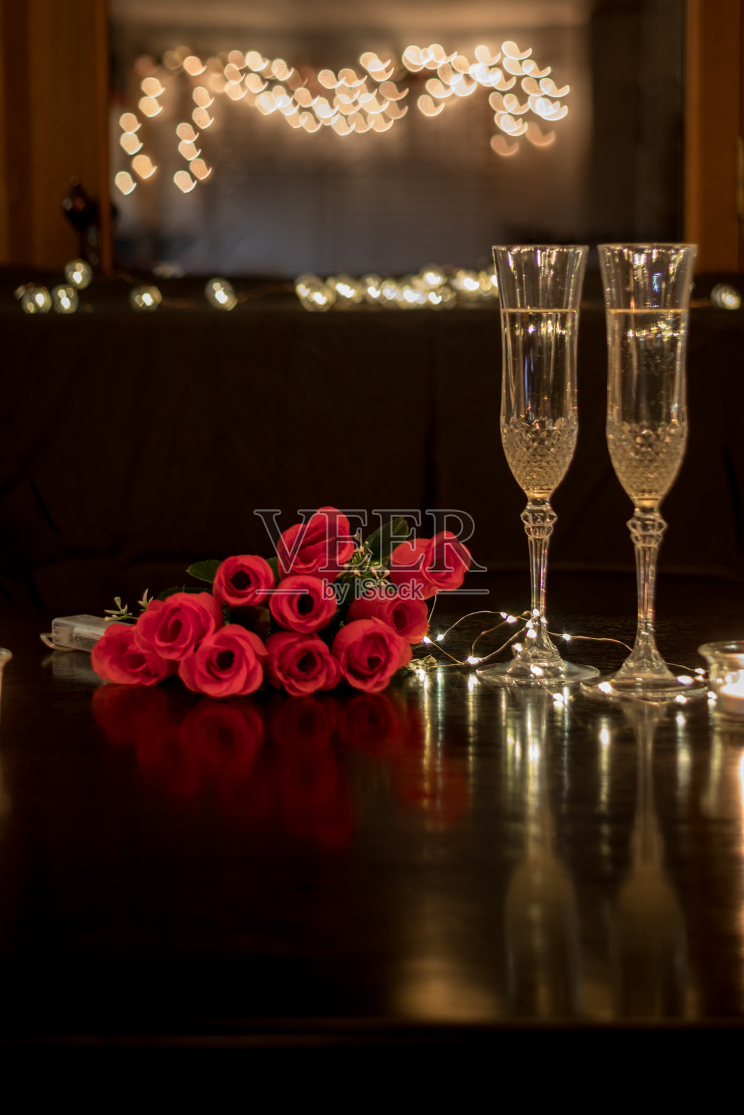 浪漫的晚餐约会之夜，深色的桌子上放着香槟和玫瑰照片摄影图片