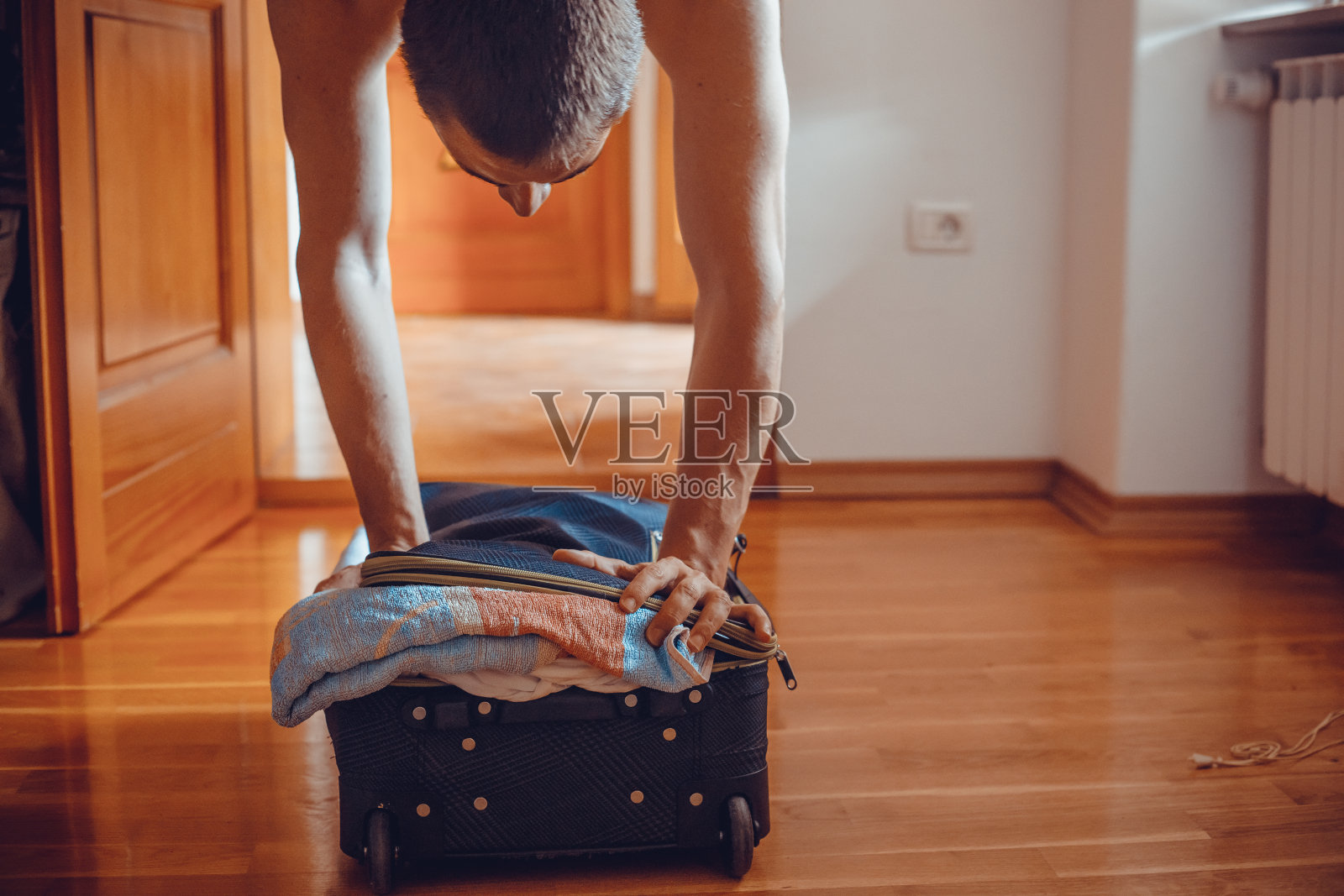 一个年轻人倒立在满箱的行李箱上，试图把它合上照片摄影图片