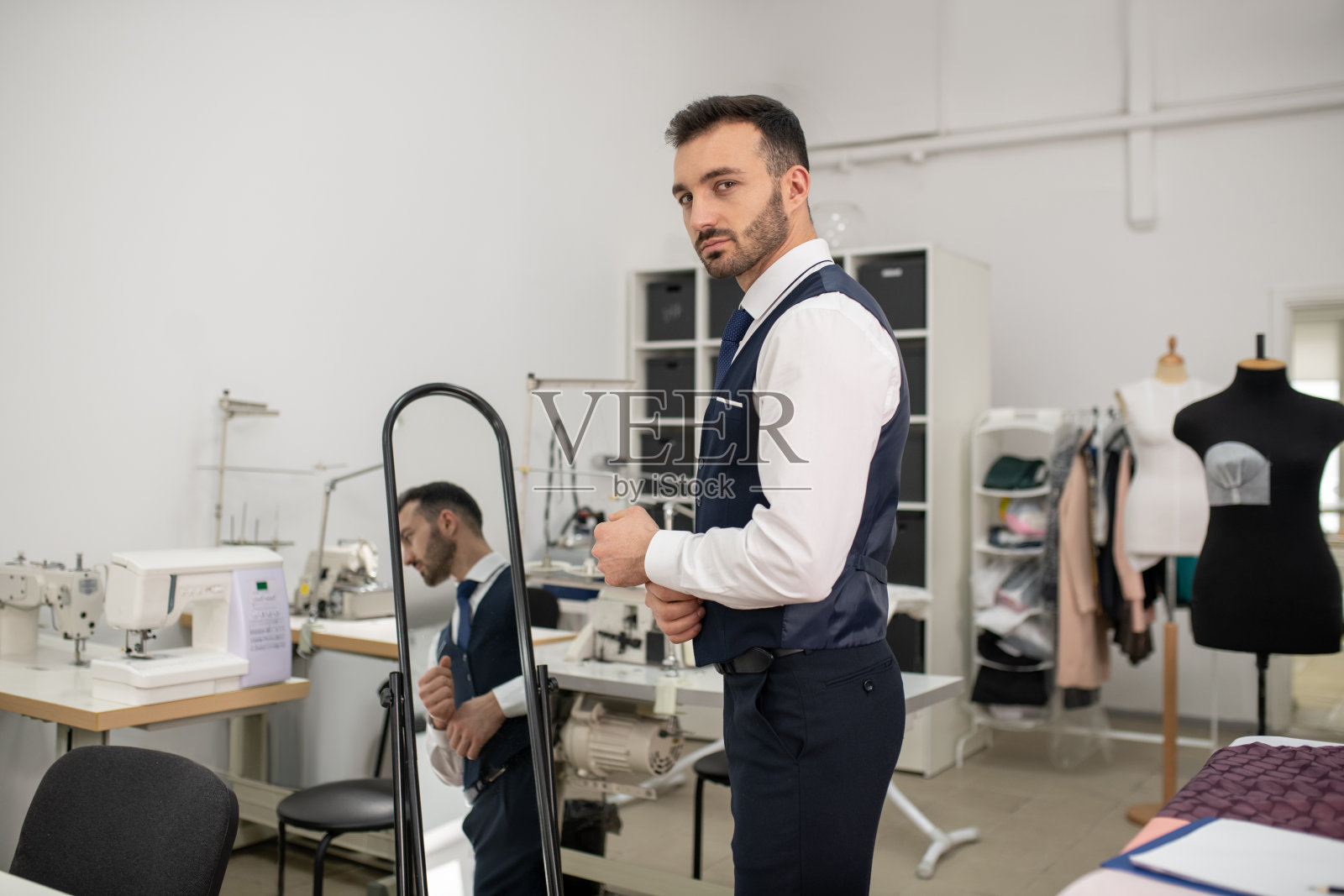 男裁缝在镜子旁整理袖口照片摄影图片