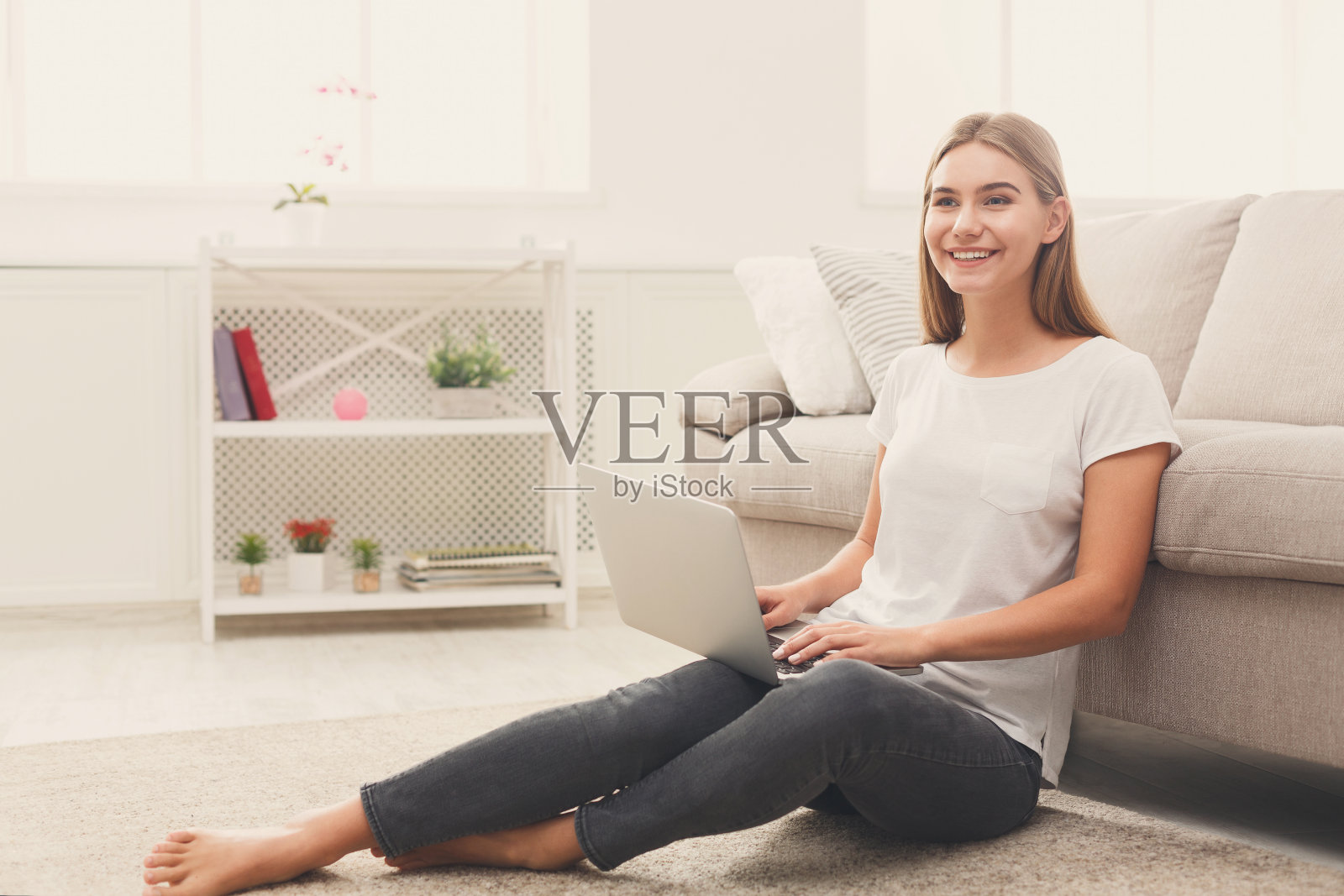 年轻女孩拿着笔记本电脑坐在地板上照片摄影图片