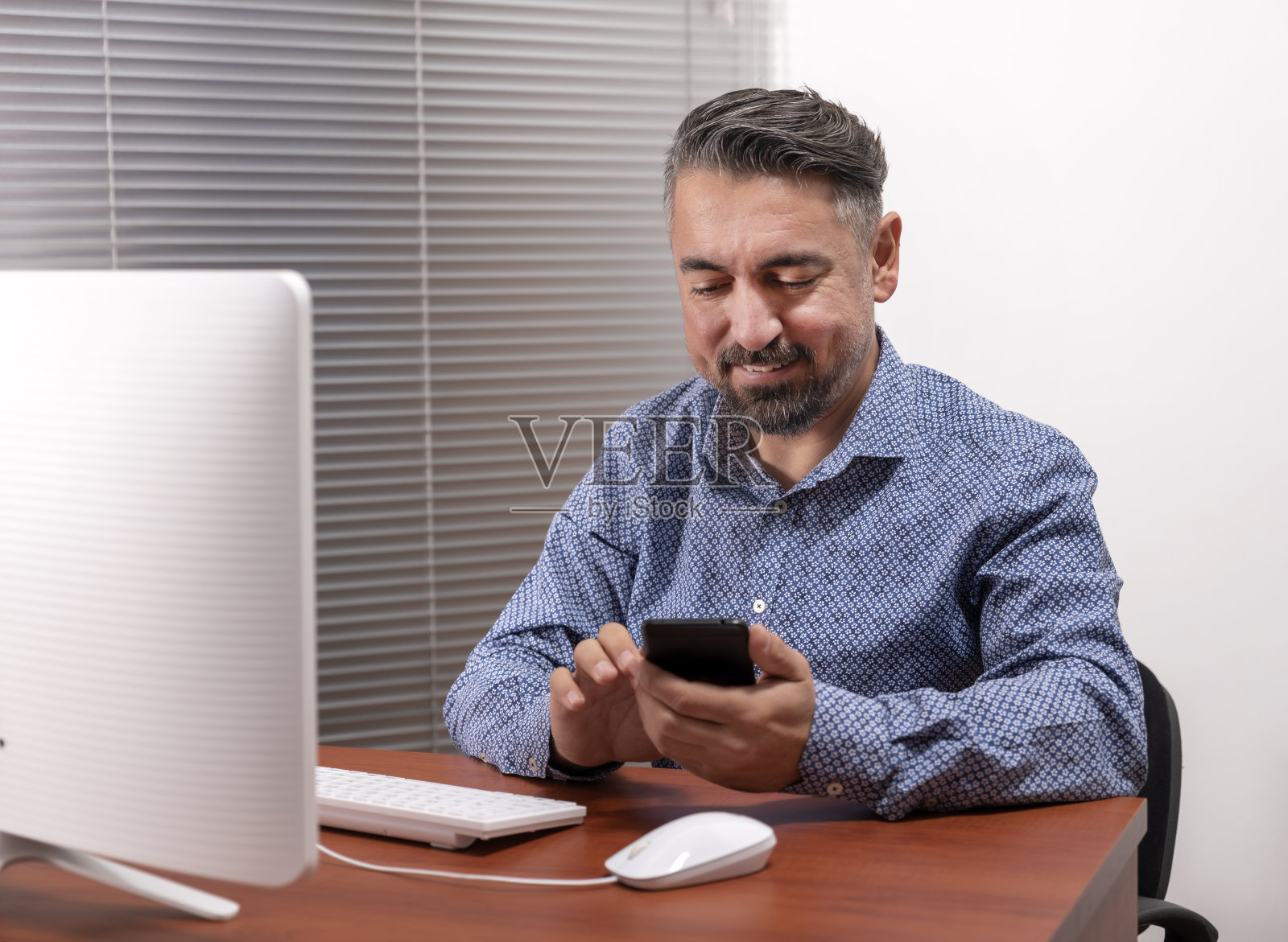 一个快乐的成熟男人使用台式电脑和智能手机的肖像照片摄影图片