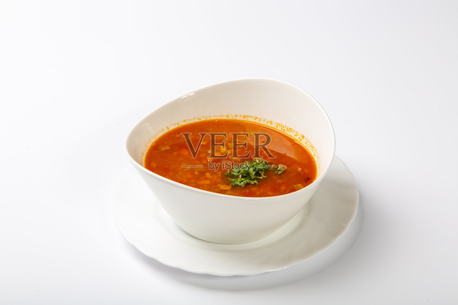 牛舌炖牛肉汤。白色背景上放着一个带有红汤的白色椭圆形盘子照片摄影图片