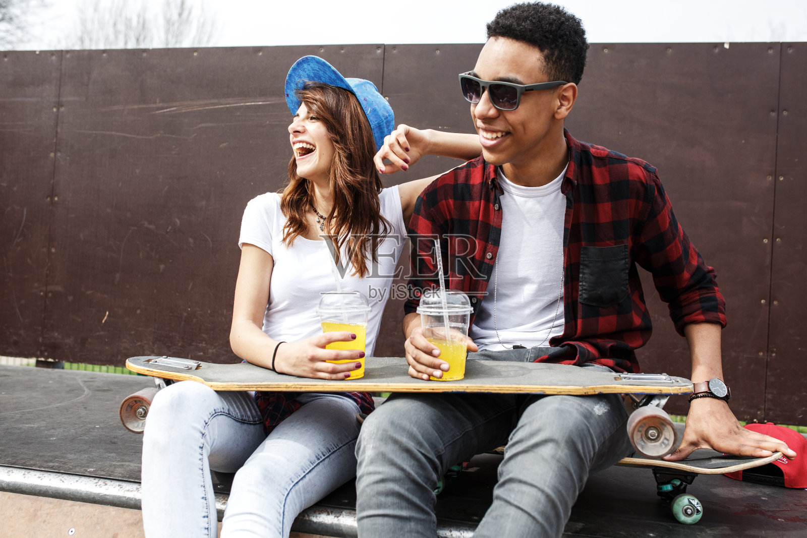 一对年轻的夫妇坐在墙边，在街上闲逛。照片摄影图片