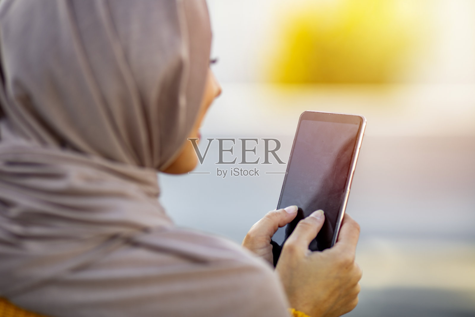 戴着头巾在户外用手机浏览互联网的女人照片摄影图片