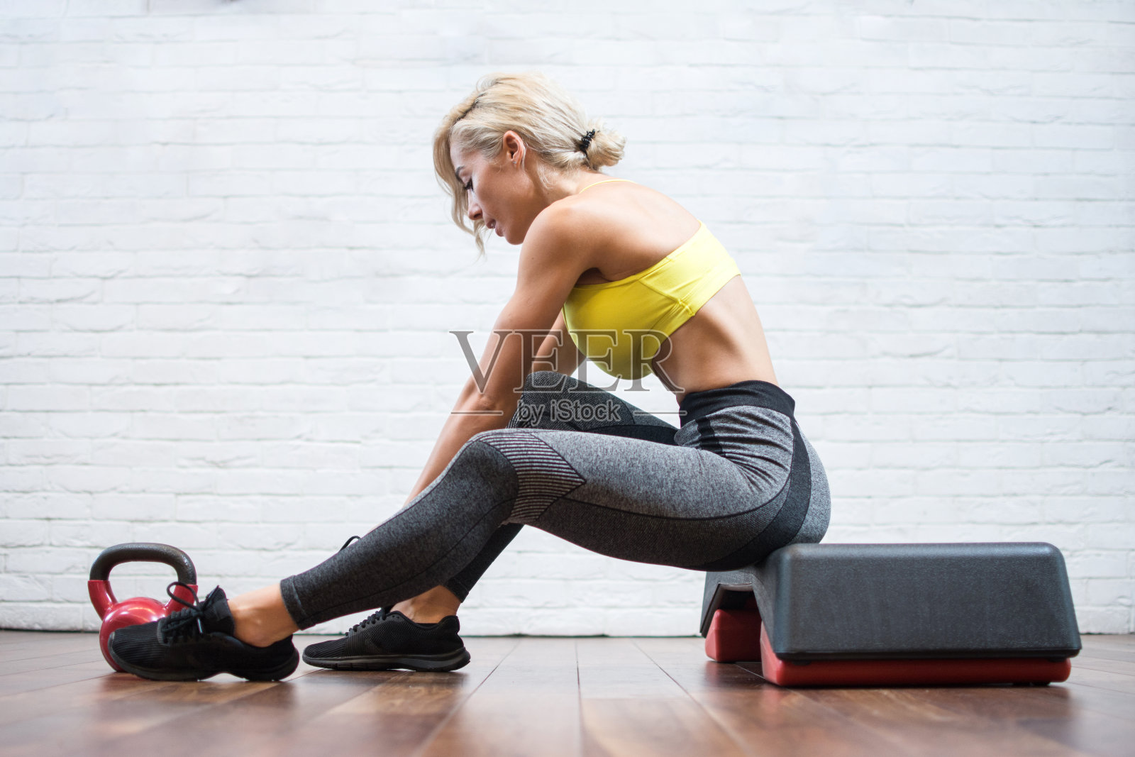 系鞋带并准备健身训练的年轻运动女性的侧视图照片摄影图片