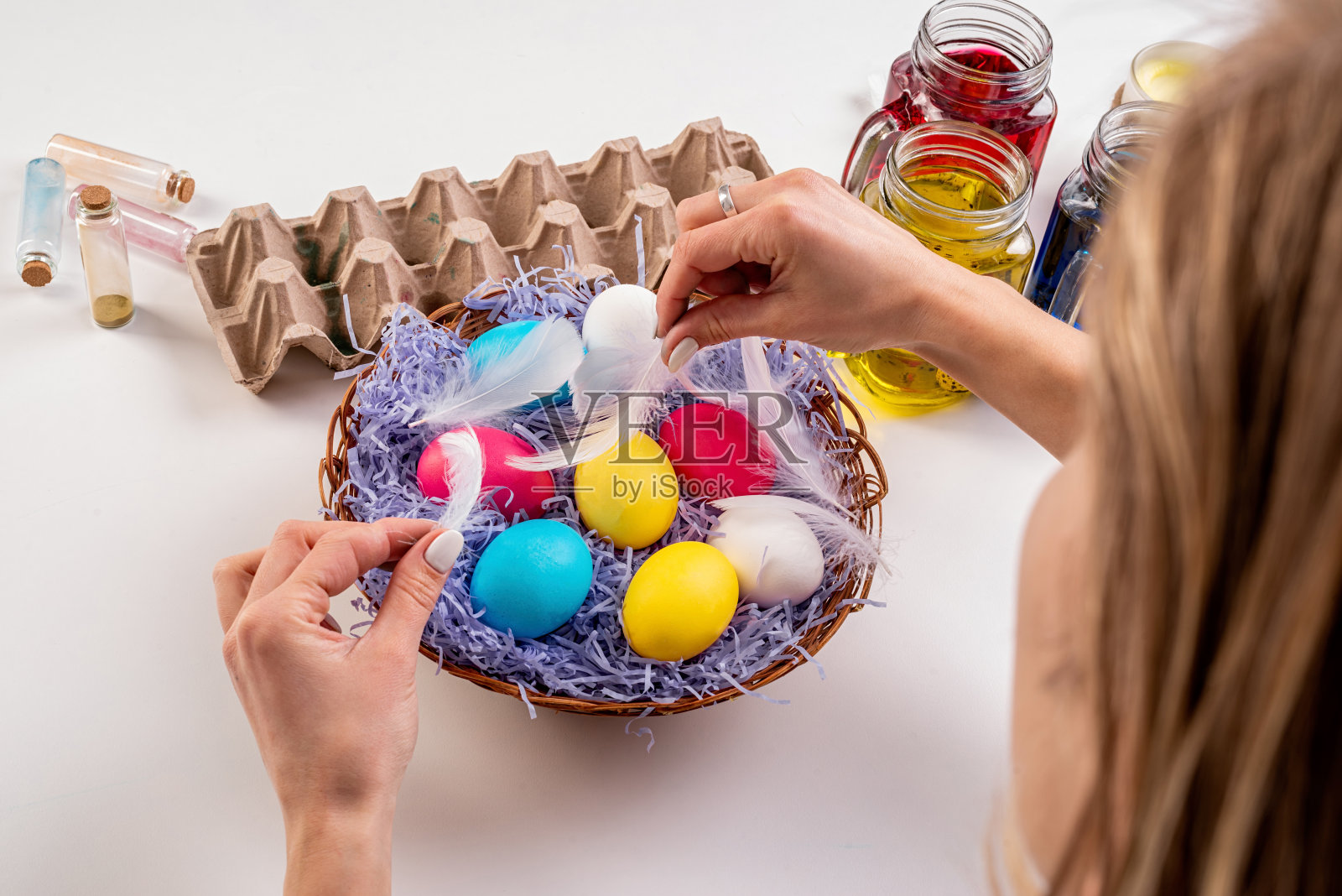 女人用彩色鸡蛋装饰复活节篮子照片摄影图片