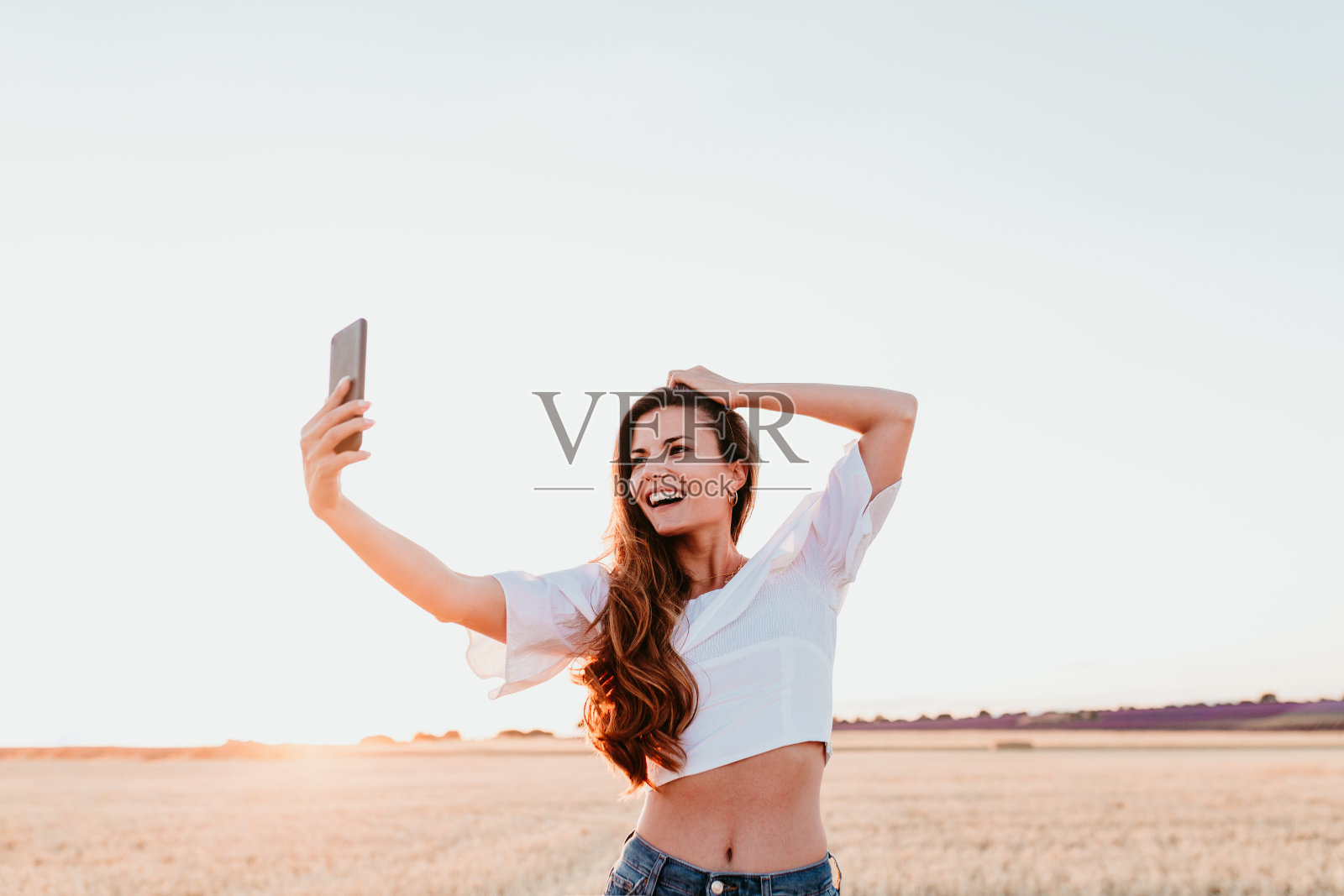 日落时分在乡村使用手机的年轻漂亮女人，科技概念照片摄影图片