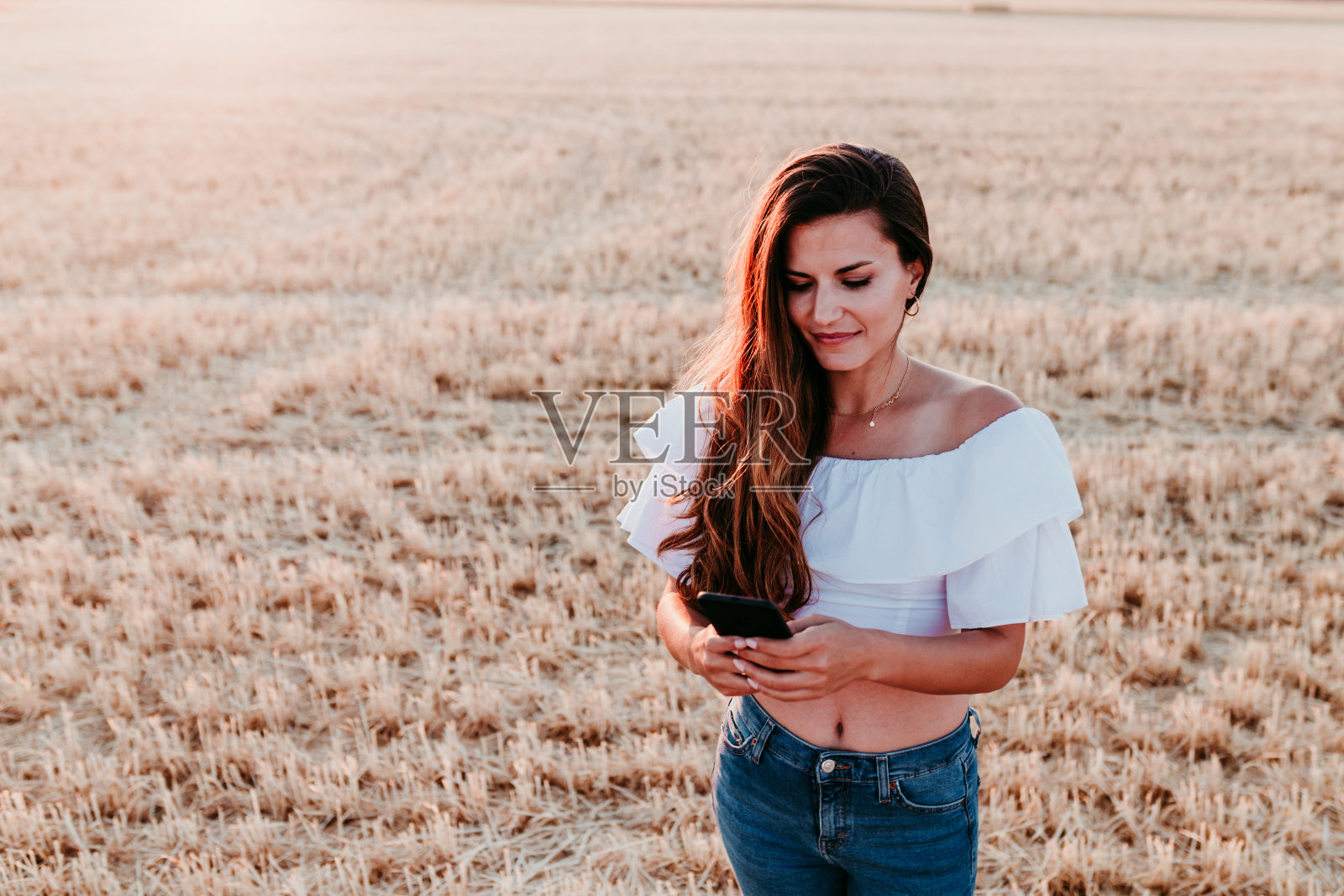 日落时分在乡村使用手机的年轻漂亮女人，科技概念照片摄影图片