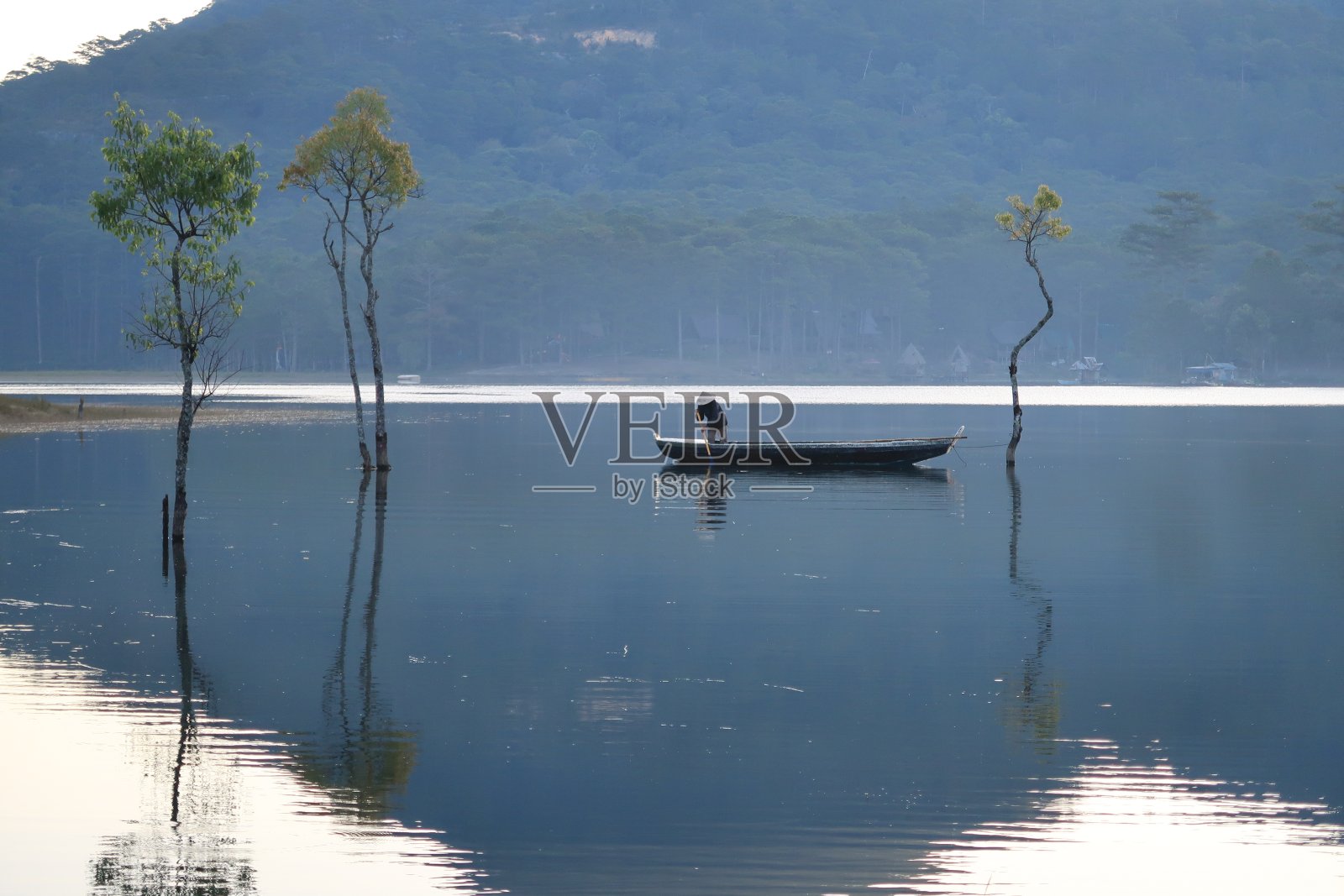 渔人和淹没的树倒影在雾湖在日出，美丽的自然季节照片摄影图片
