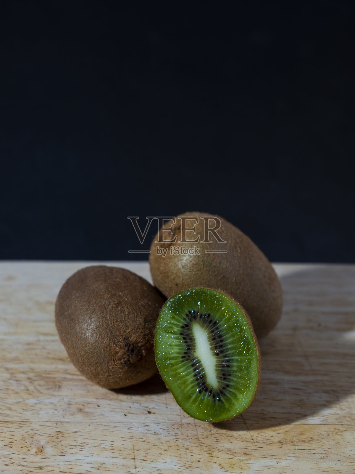 猕猴桃静物竖版图，其中一个切成两半照片摄影图片
