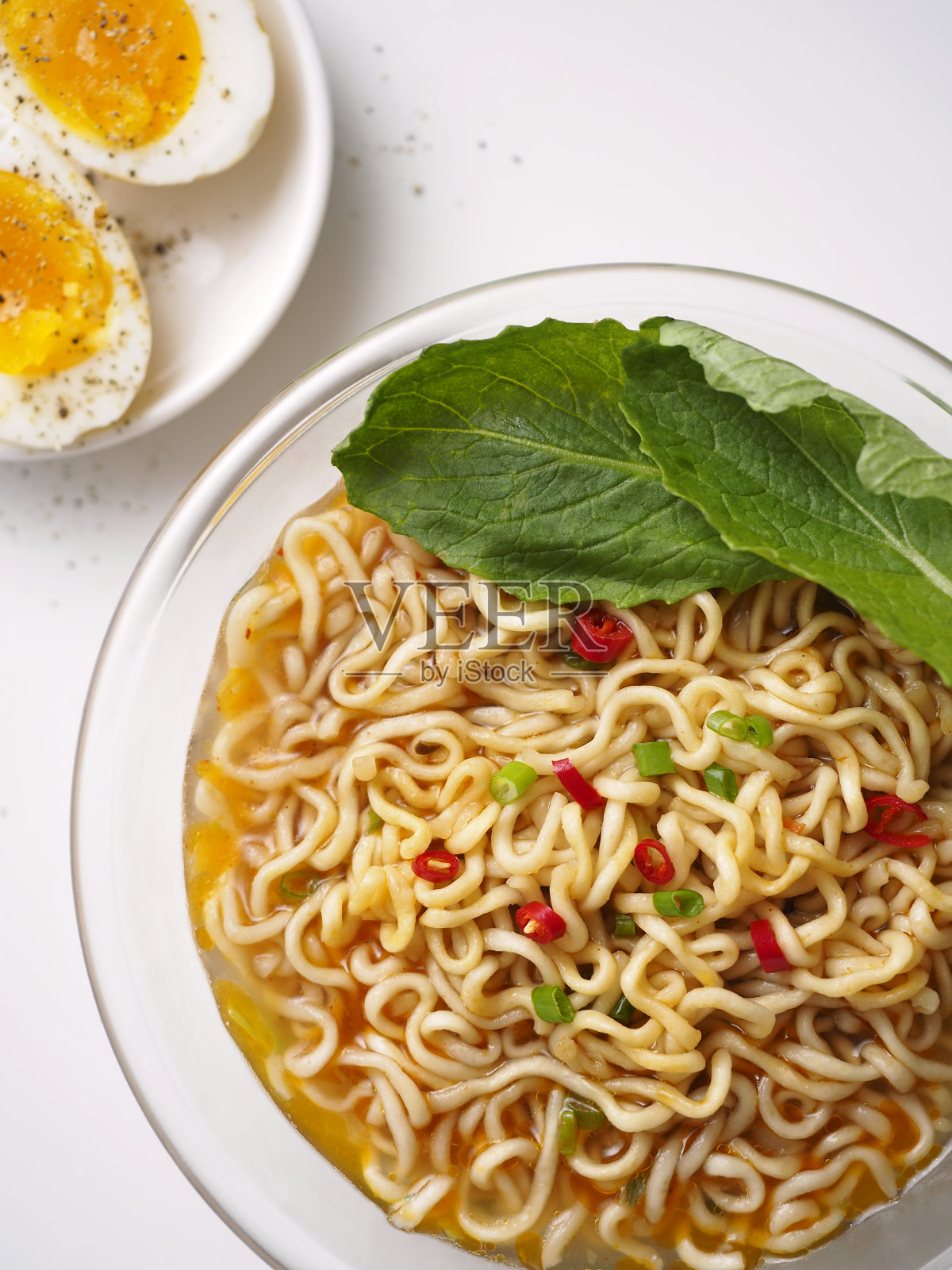 方便面在碗与新鲜的绿色蔬菜和煮鸡蛋。照片摄影图片